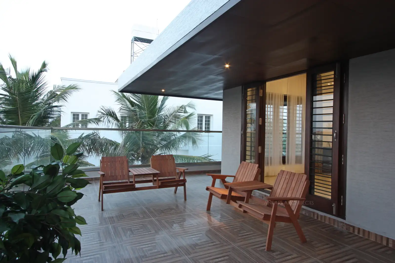 The flooring lemds a geometric pop, the space exudes a contemporary vibe with cosy outdoor furnitures along with plush green vibes.
