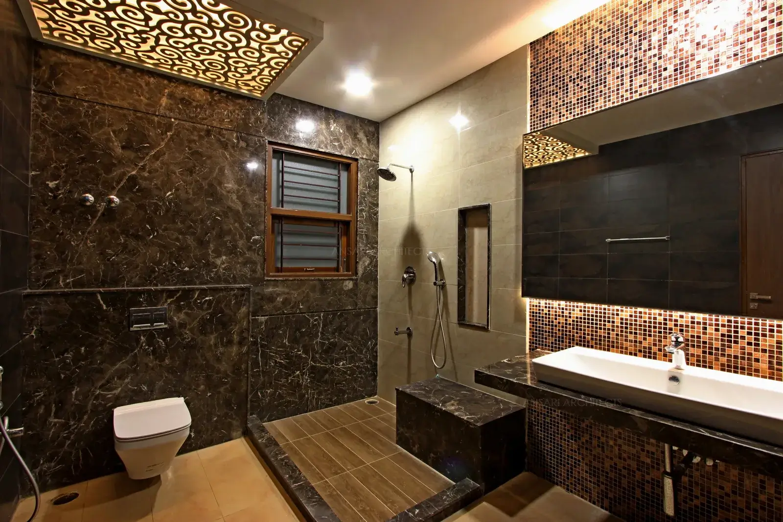 The scheme gives this bathroom a bigger and brighter space. Vertical storage niches in the wall makes clever use of floating space. Dark tile finish infuses a hint of colour with wall mounted toilet and a curbless shower, leaving the floor space clear.