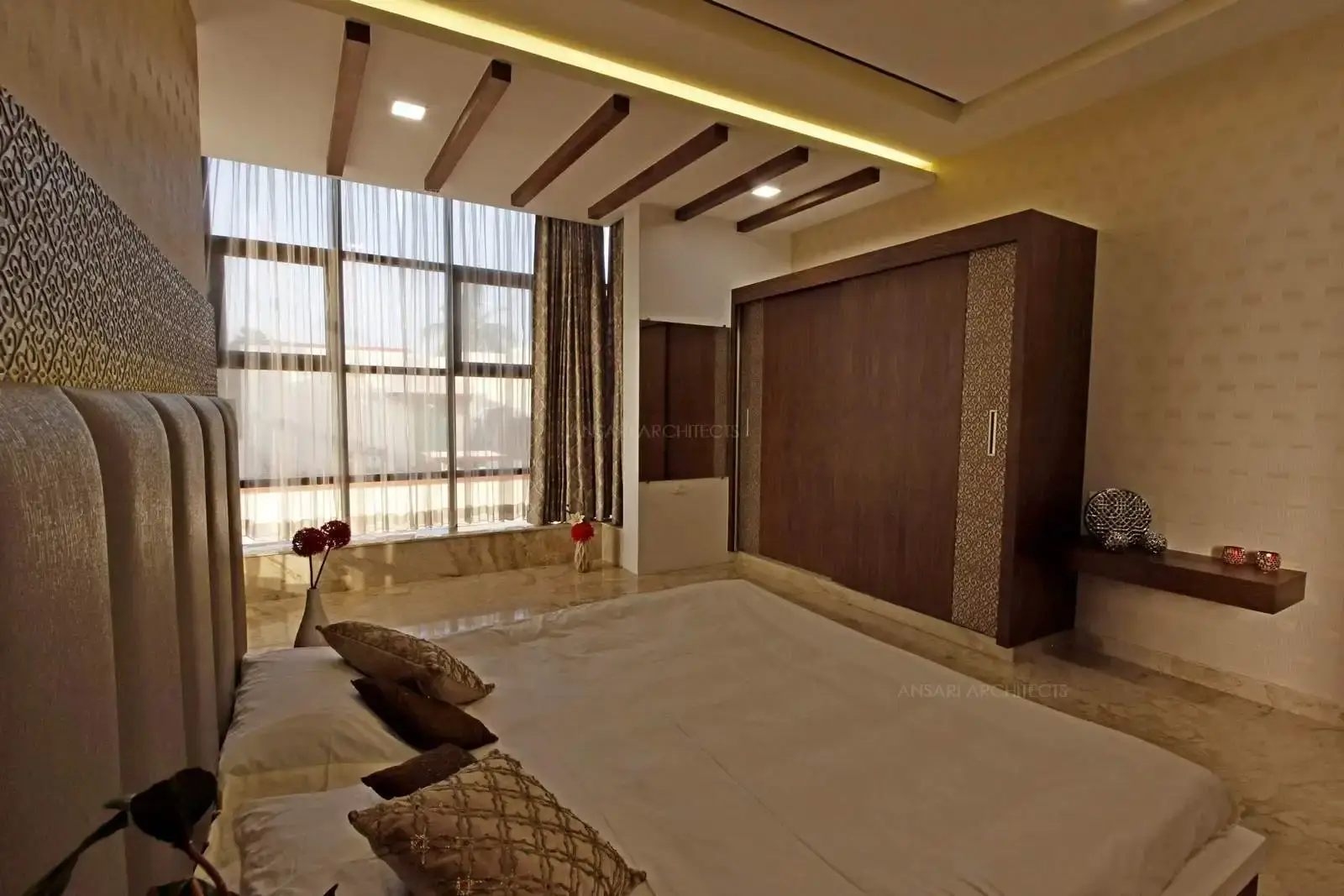 The monochrome horizons of this space epitomises contemporary style. The splendid gold lining work enriches a royal theme. The dark veneer finish wardrobes evoke boldness and the false ceiling design with wood planks and cove lighting embraces the mood of the space.