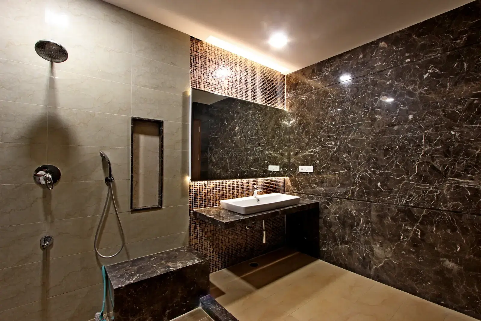 Plenty of recessed lights compensate for the absence of natural light. The backlit mirror lights add a element of grandeur. The monochromatic colour scheme enhances the eclectic bathroom.