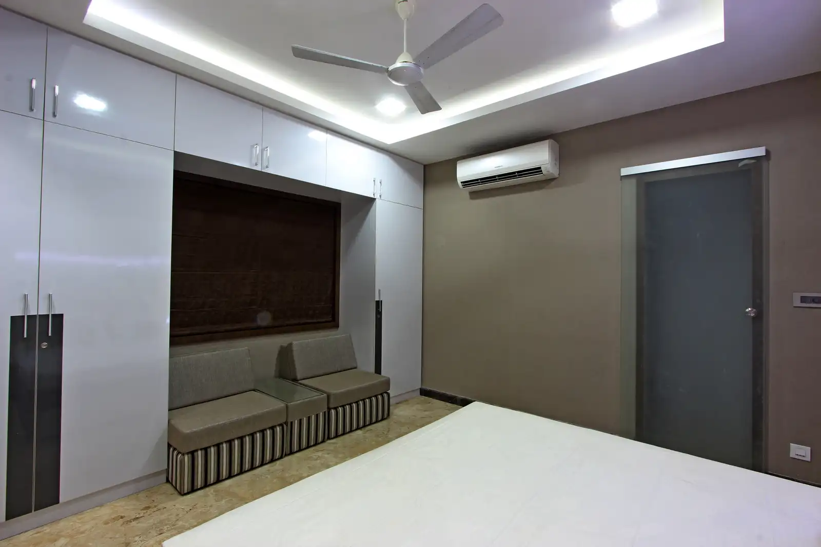 The couches recessed internally with a rustic colour effect creates a soothing space. with the wardrobes for storage with light tones plain finish occupying the full wall