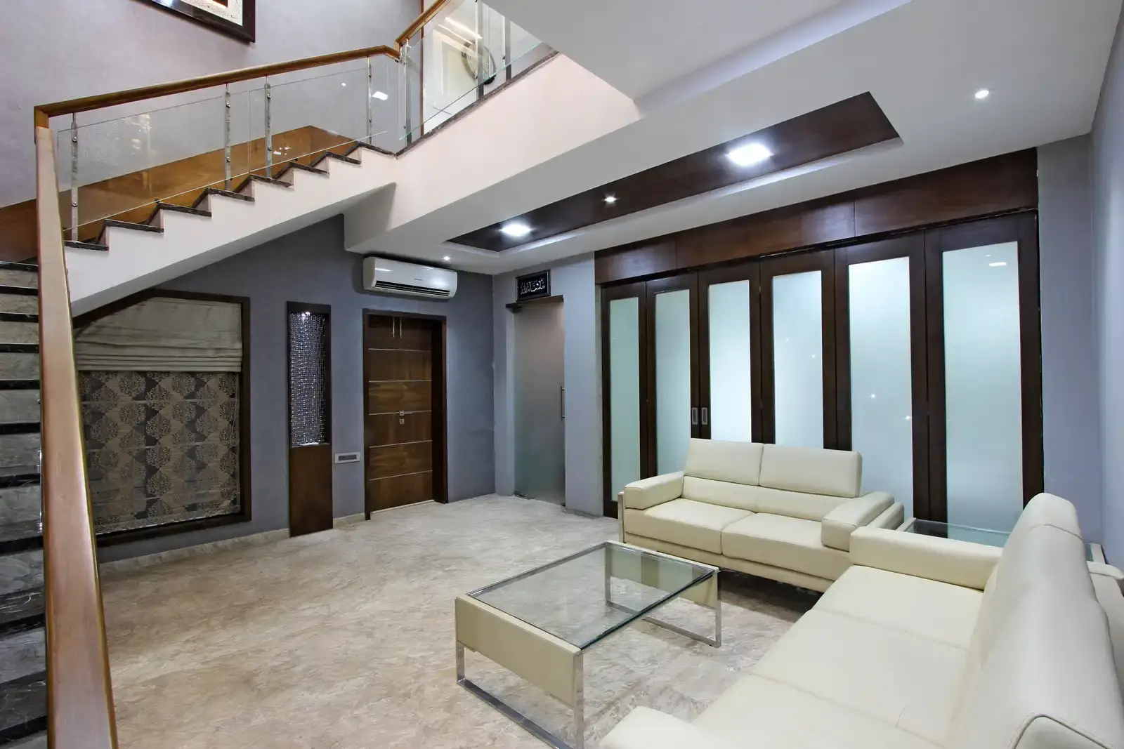 The exposed walls with rectangular niches with glass and recessed lights.The glass partition acts as a welcoming space.