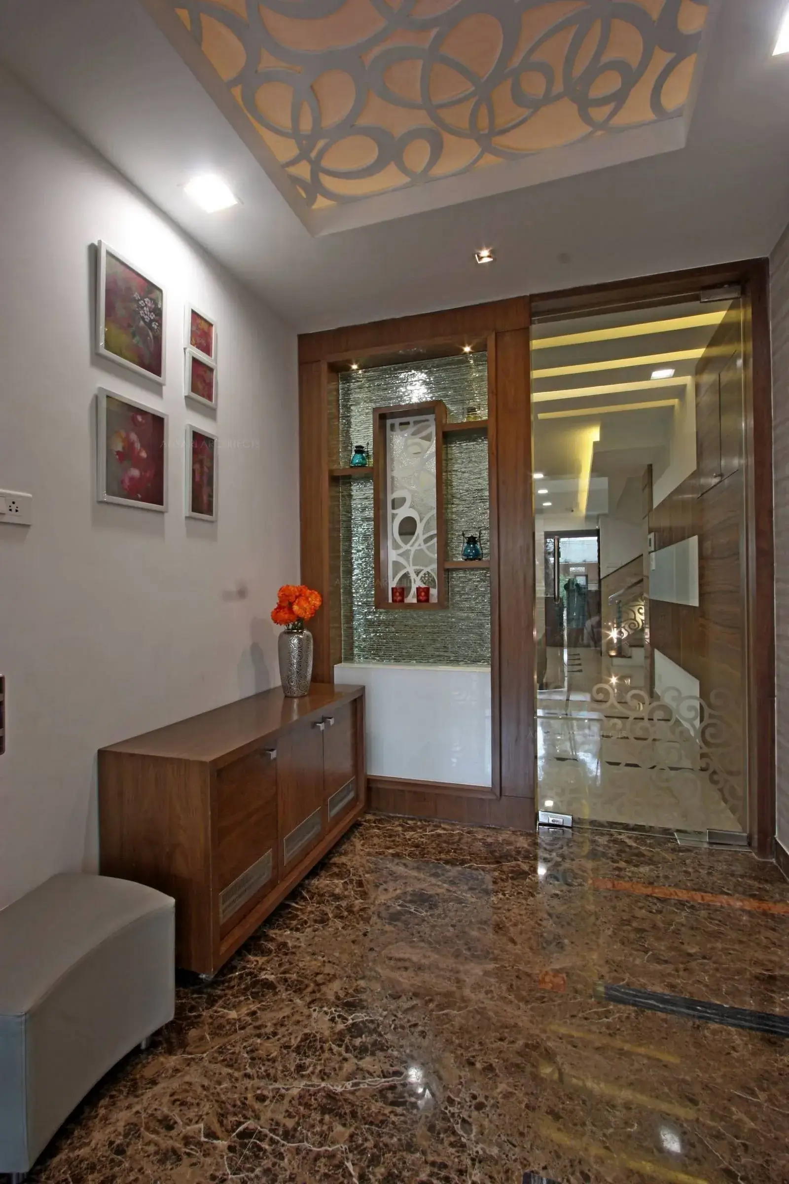 The Entrance lobby with glass display unit for ornamentations. The ceiling creates a rhythmic pattern with highlighting spot lights. Every piece of art is sourced and carefully selected.