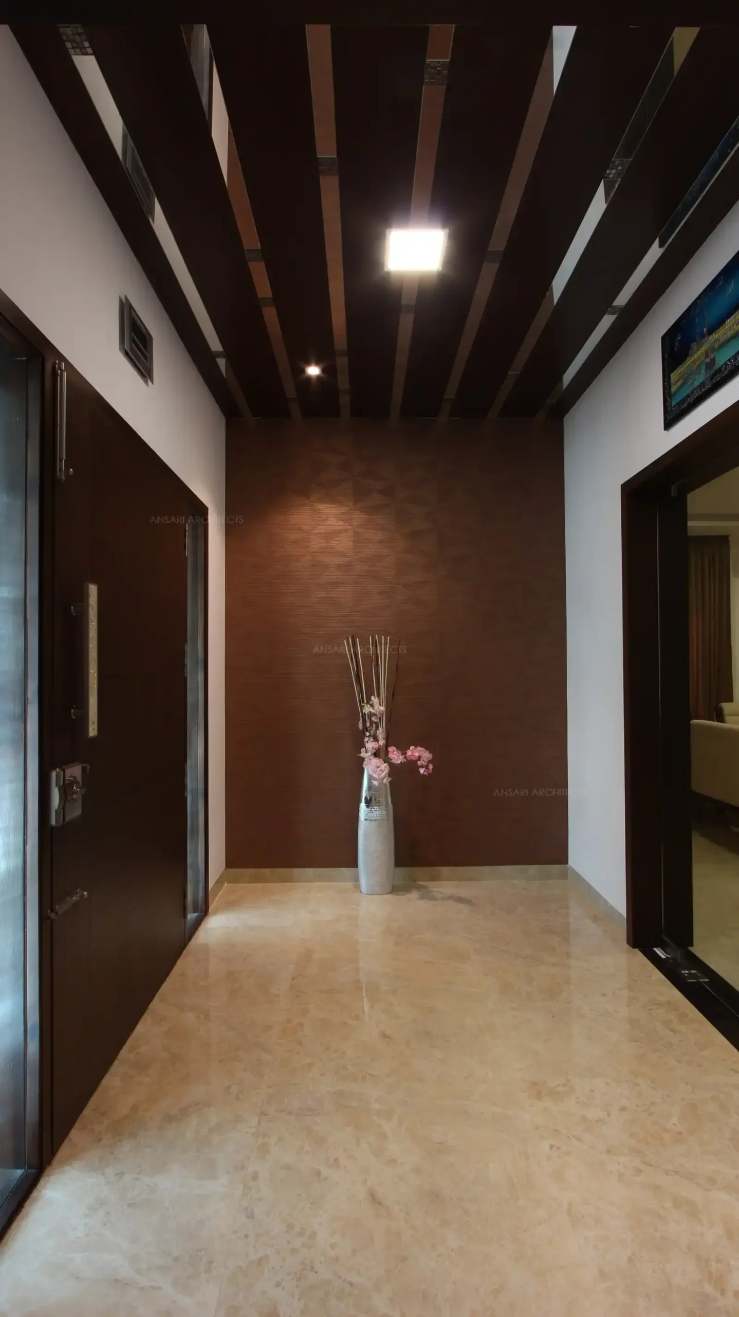 A simple foyer with decor wall highlighted by wallpaper and wood batterns over the ceiling, natural light pours in through the openings and it sets a mood with rustic printed tiles.
