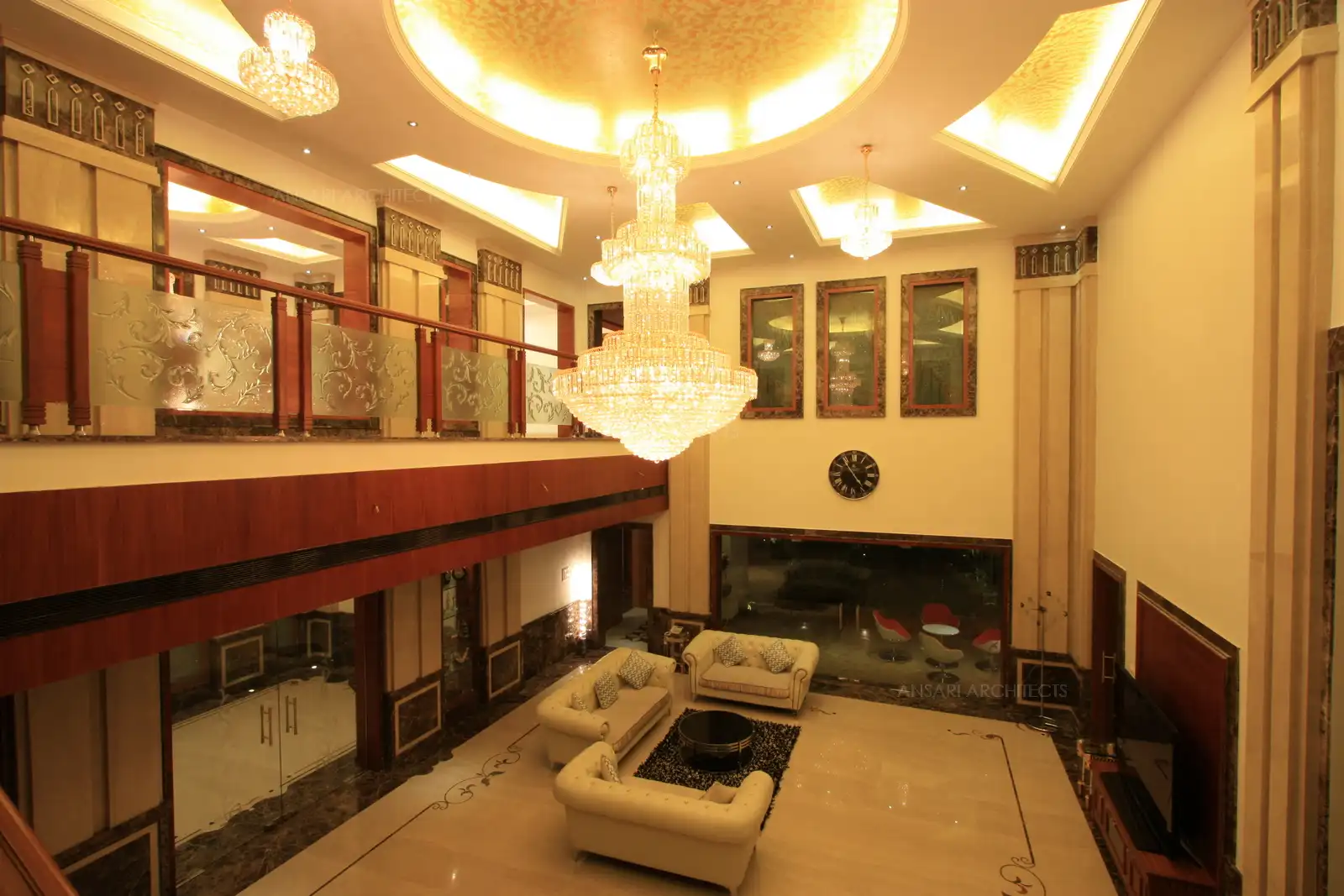 View of posh double height living area designed in luxurious chandliers, glass handrails and marble cladding.