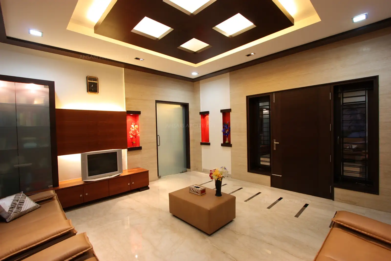 Drawing room in the front has a simple yet rich look with the use of dark shade veneer and marble cladding on the entrance wall.