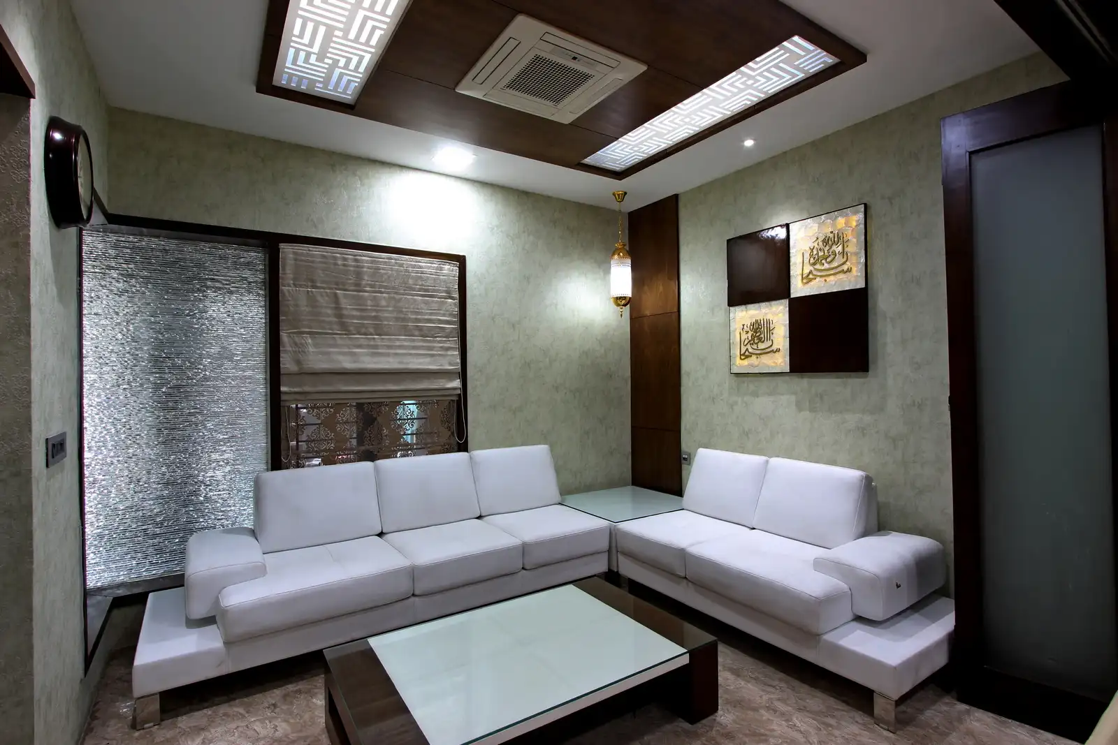 The reception area is a relaxed welcoming space with custom furnitures and the sleek false ceiling with veneer glow lights arranged centrally, grounds the spaceoffering contrasts to wallpapers, whites and deep veneer.