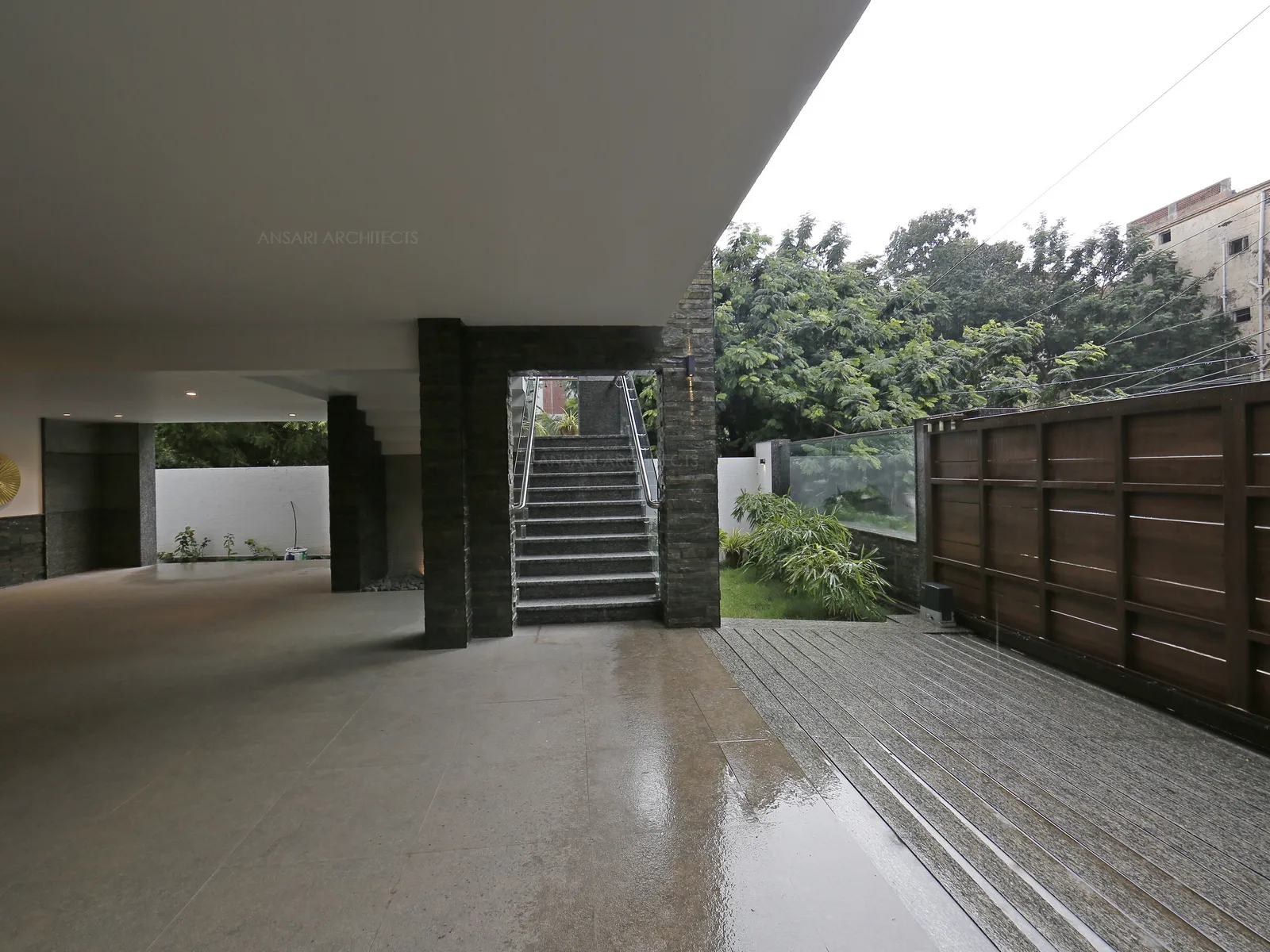 The entrance porch is set on with stone cladding and marble flooring to create a contemporary home with composition of plants , pebbles , stone claddings.