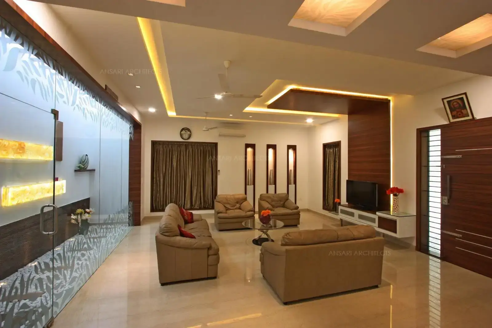 The courtyard space with decorative elements with soothing golden touch pops out wall. Niches are highlighted with lights which bring more depth to the decor and definitive lines. The ceiling to floor cladding with the backlit tableau forms a backdrop seeking to separate wood from the wall.