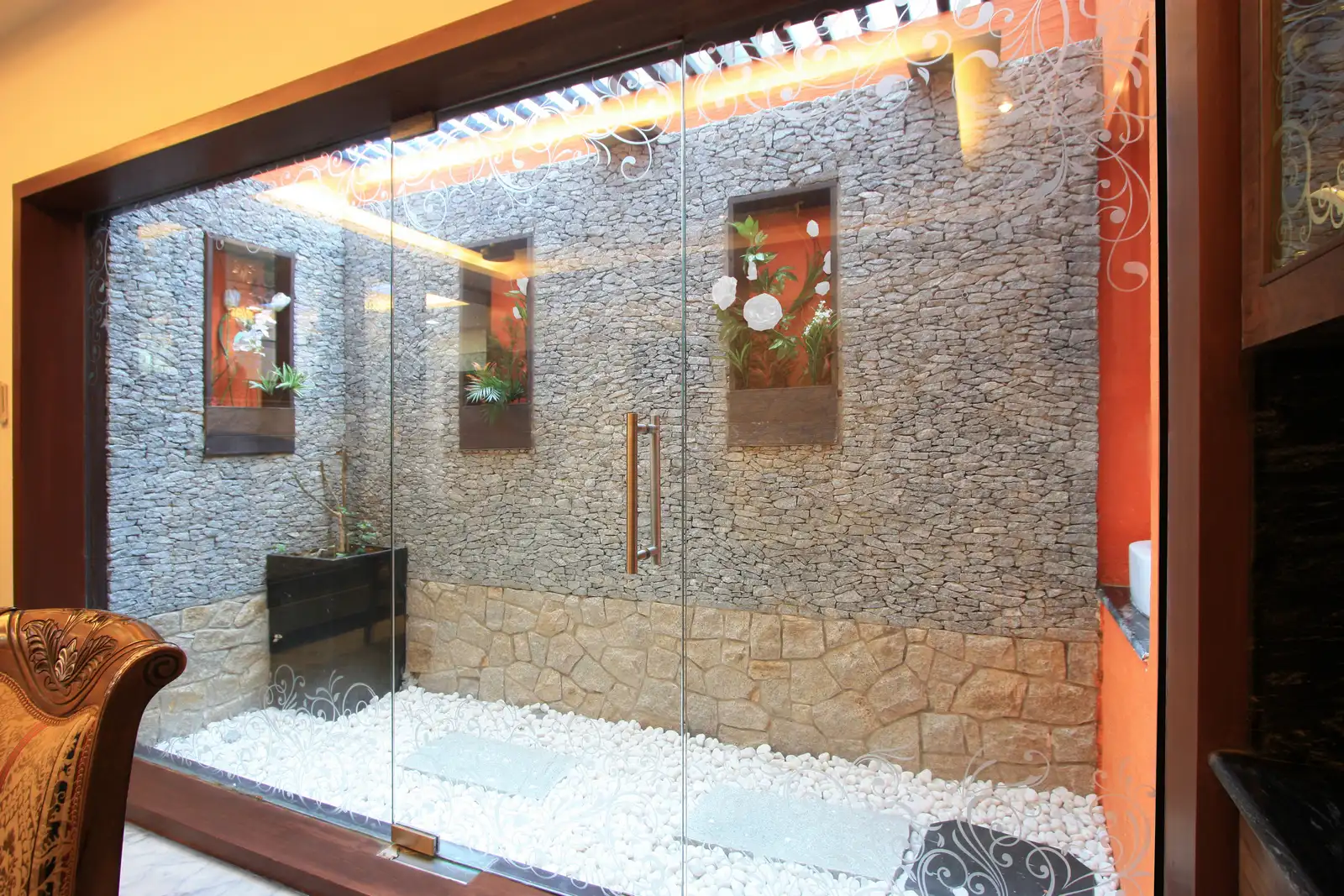 A courtyard planned in the dining area is well designed with stone cladding and contrast wooden niches as planter boxes