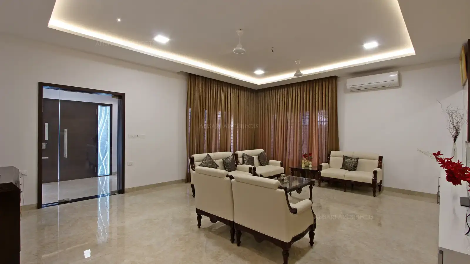 The room is rich in detail, including the whitw sofa, side table while the touches of black, beige add contrast without overriding the purity of the white room.