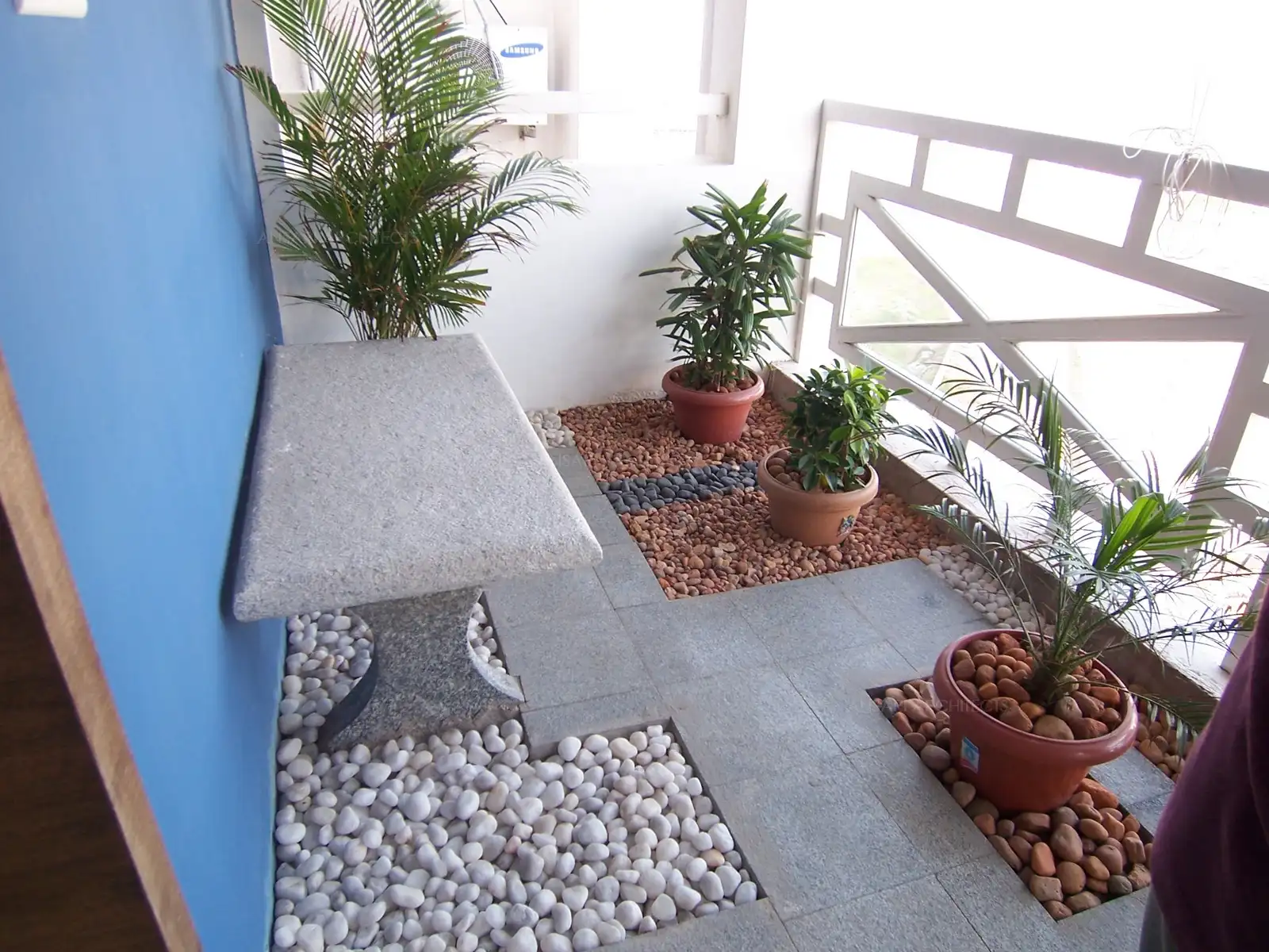 Balcony in the living room has been designed with dry landscape flooring with pebble beds and stone bench.