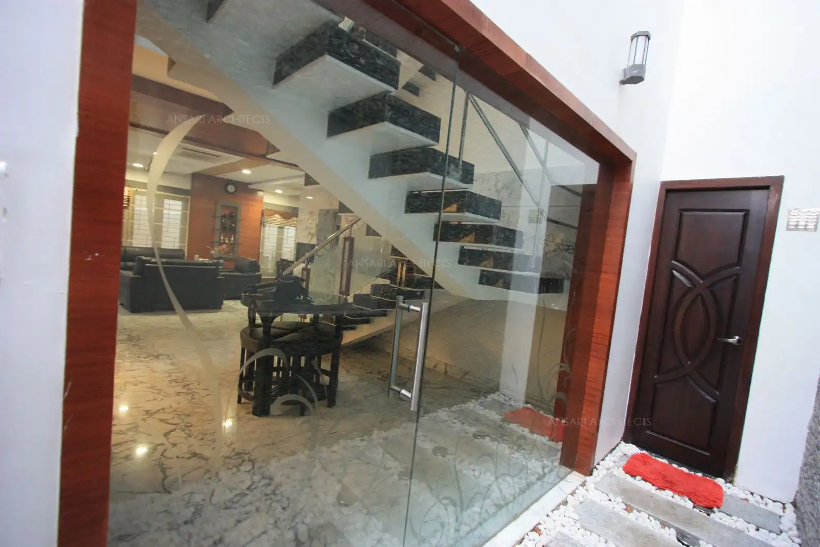 View of courtyard showing the staircase area in living room through a clear glass.