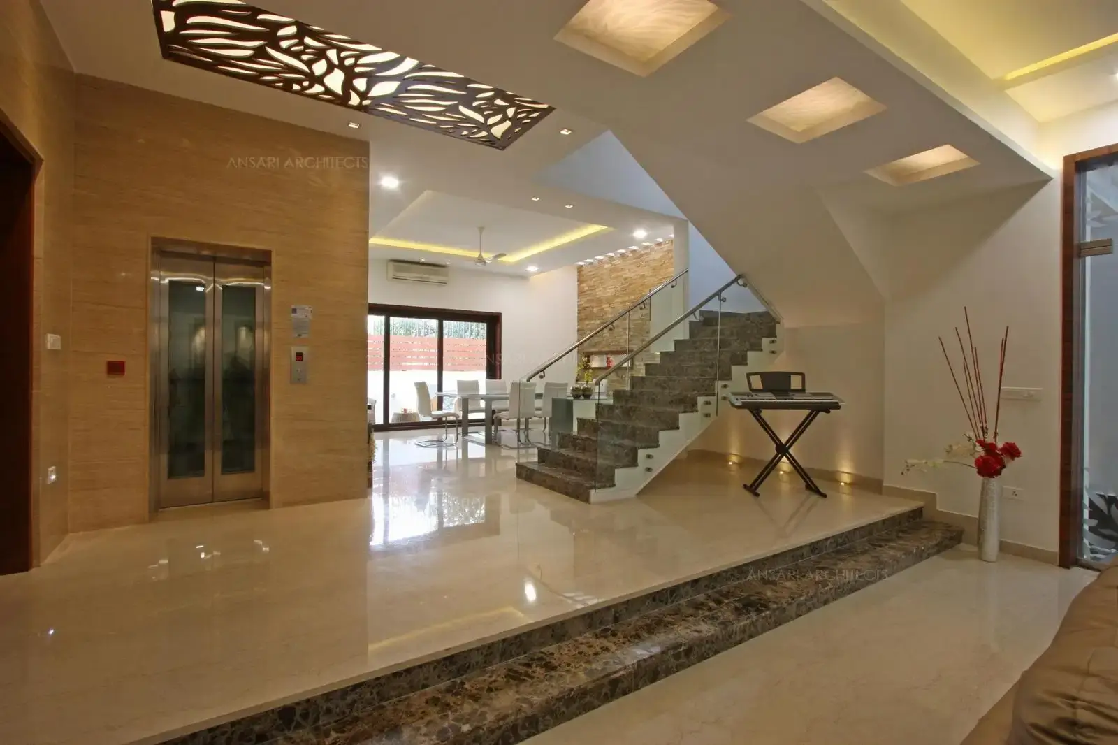 The elevated spaces with a staircase literally shapes the space, to make a sculptural stand out, cladding has been done in marble to differentiate the space from the rest of the room and the walls in a contrasting colour. Flooring lights behind staircase highlight area.