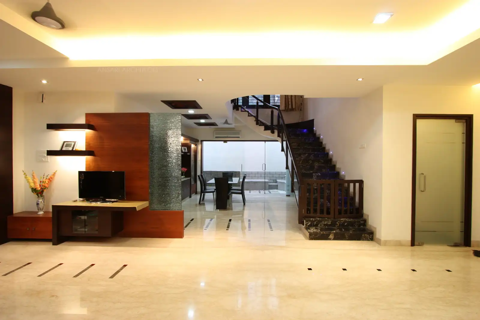 Wood panelling with butched glass behind the TV unit also acts as a partition to the dining area