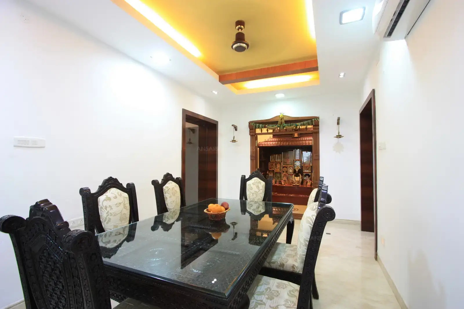 The dining room is furnished with traditional wooden curved chairs, and glass top wooden carved dining table