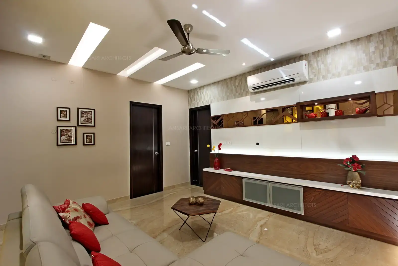 The family room with central element positioning furniture and off white colour tone , wooden panelling with directional grains providing a contemporary design with shelving units.