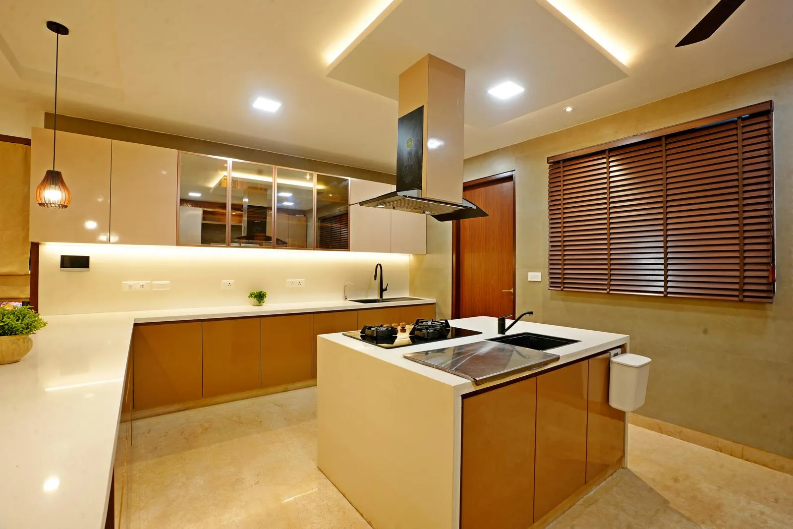 The kitchen area ( 18'0" x 13'6" sq. ft ) features a U-shaped layout with a central island, optimizing workflow, storage, and accessibility. Glossy beige cabinets, white quartz countertops, and layered lighting create a bright, functional, and elegant cooking space.