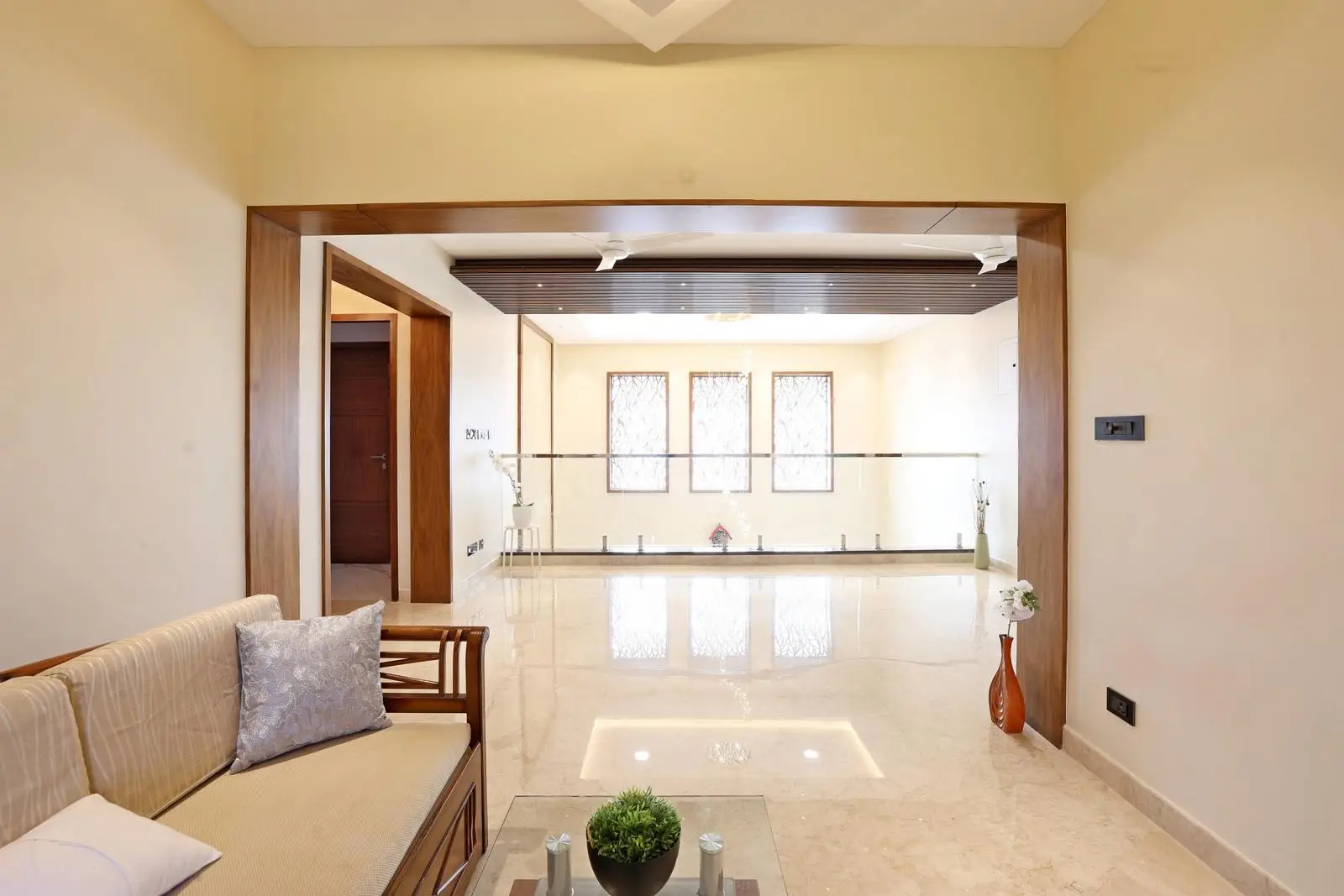 A wooden frame partition defines each zone without closing it off. Three large windows fill the space with natural light, perfect for reading, studying, or relaxing.