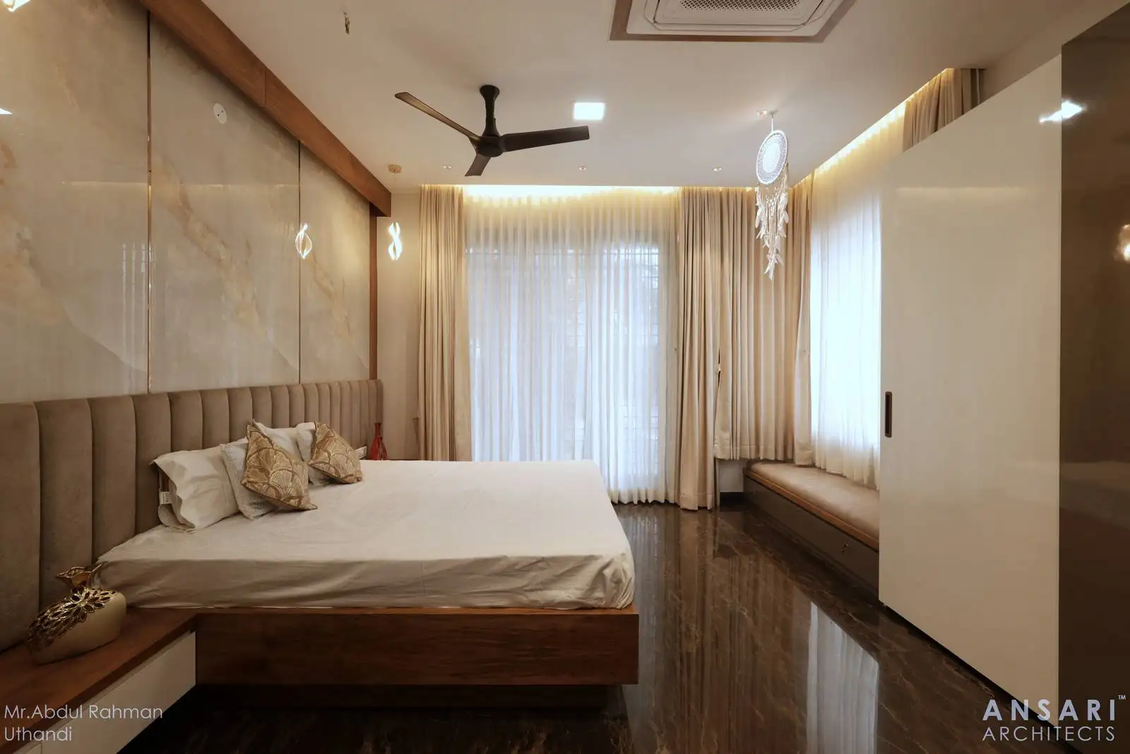 The room features two prominent window elements: a large main window with sheer curtains and a cozy sitting window nook to the side, both allowing abundant natural light.