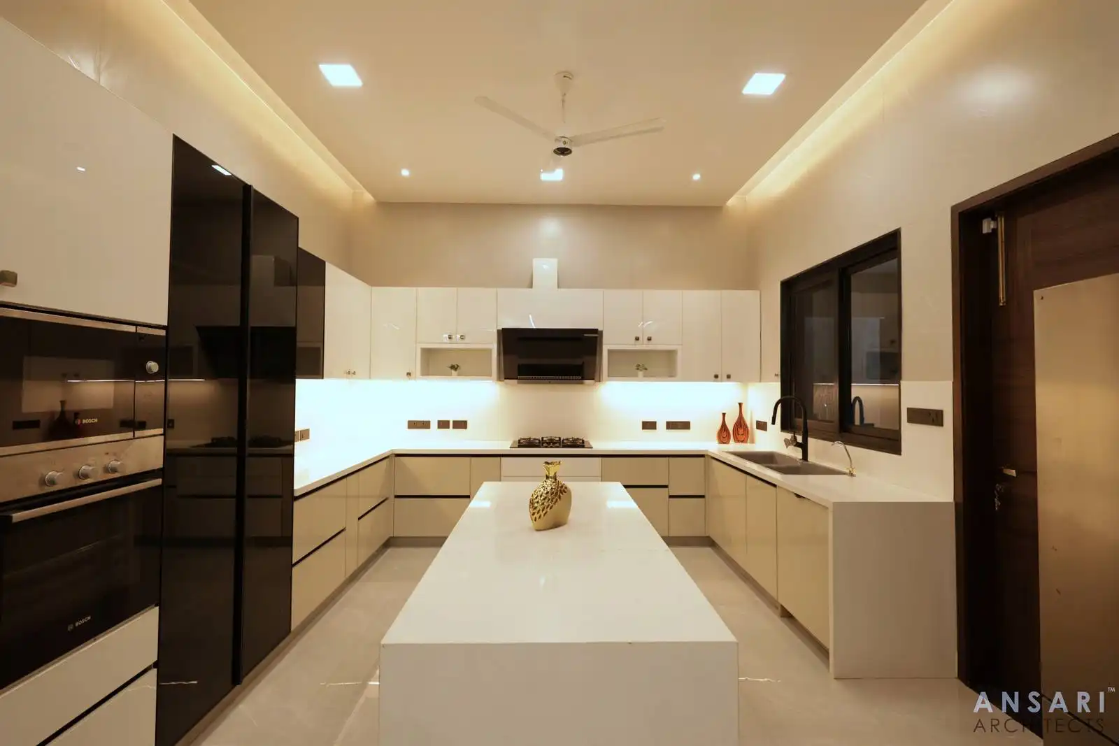 Sleek white kitchen with central island, black accents, and integrated lighting for a refined, functional layout.