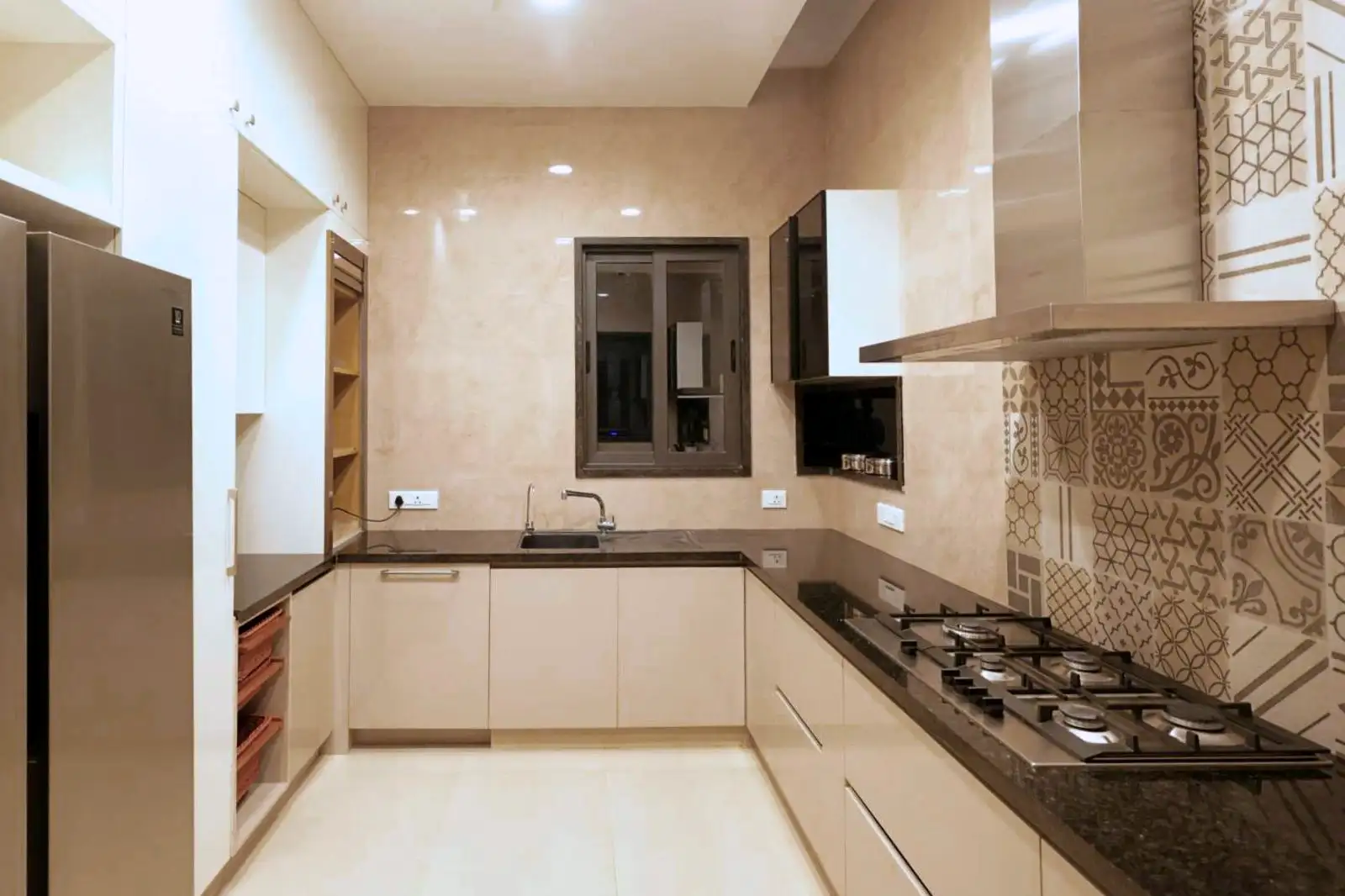 The kitchen is organized in a U-shape, maximizing counter space and storage along three walls, creating an efficient workflow. The sink is centrally located under a window, allowing for natural light and ventilation while washing or prepping food.