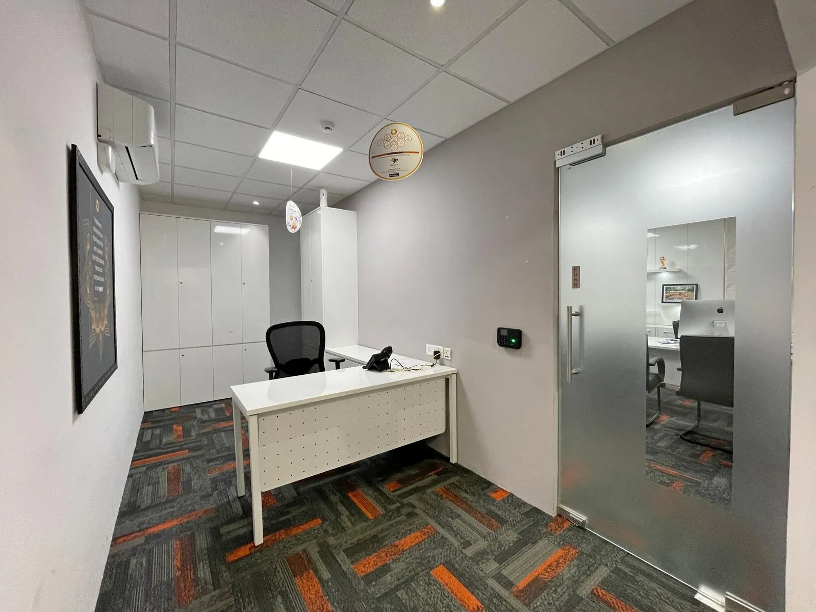 The secretary cabin features a linear layout with ergonomic seating, integrated storage, and glass partitions. Clean finishes, recessed lighting, and subtle accents create a functional, modern workspace.