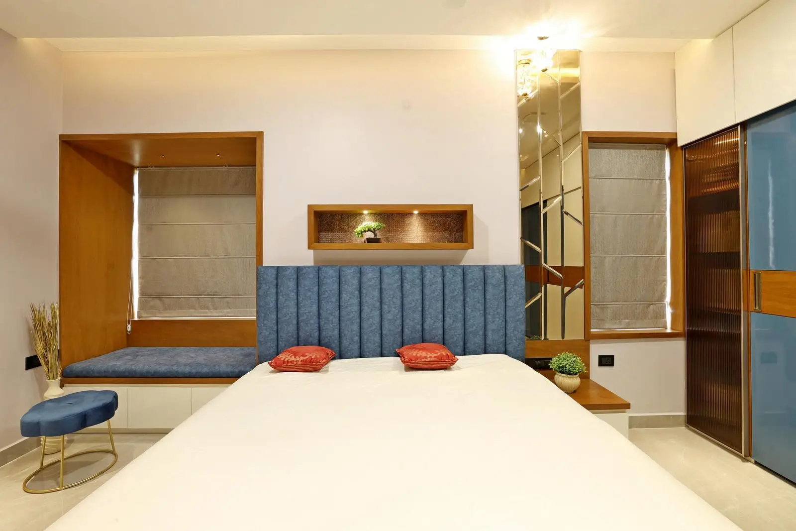 The 1st daughter’s bedroom features a central bed with symmetrical windows, built-in seating, and a mirrored panel. Warm wood, beige walls, and deep blue accents create a balanced palette. Floating furniture, recessed lighting, and integrated niches keep the space modern, functional, and elegant.