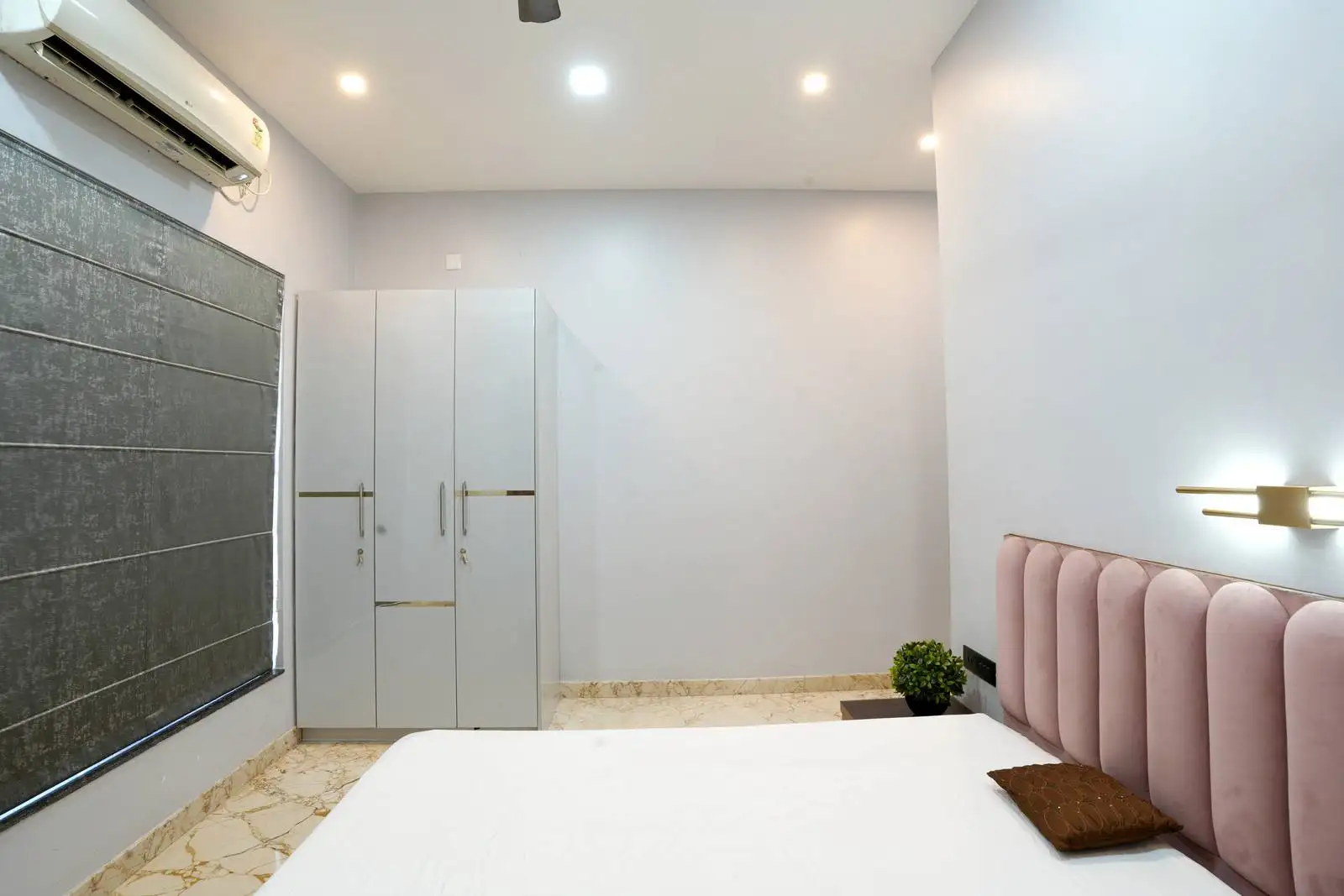 A soft-toned bedroom featuring a plush fluted headboard and patterned marble flooring that adds texture and warmth.