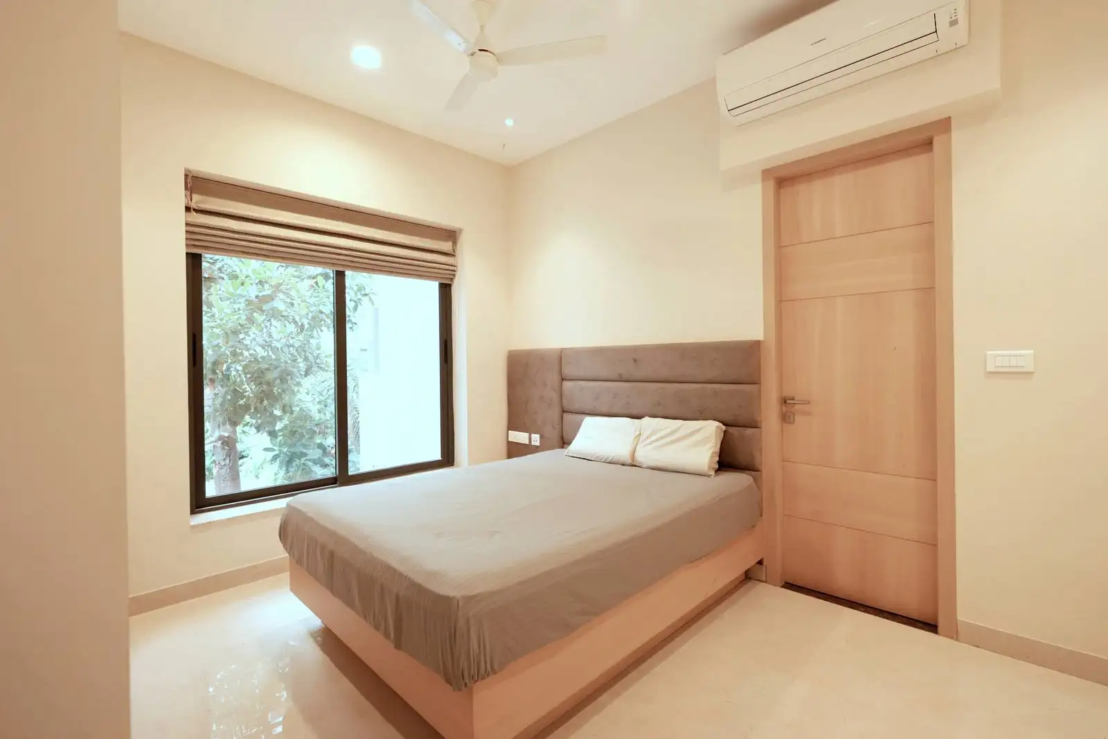 The bed is centrally placed against the main wall, featuring a padded headboard for comfort and a subtle touch of luxury.