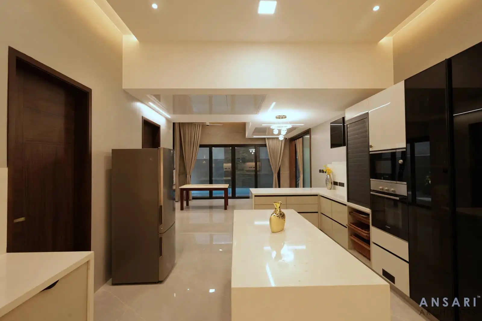 Large windows enhance natural light, connecting the space to the outdoors and emphasizing airy, modern kitchen.