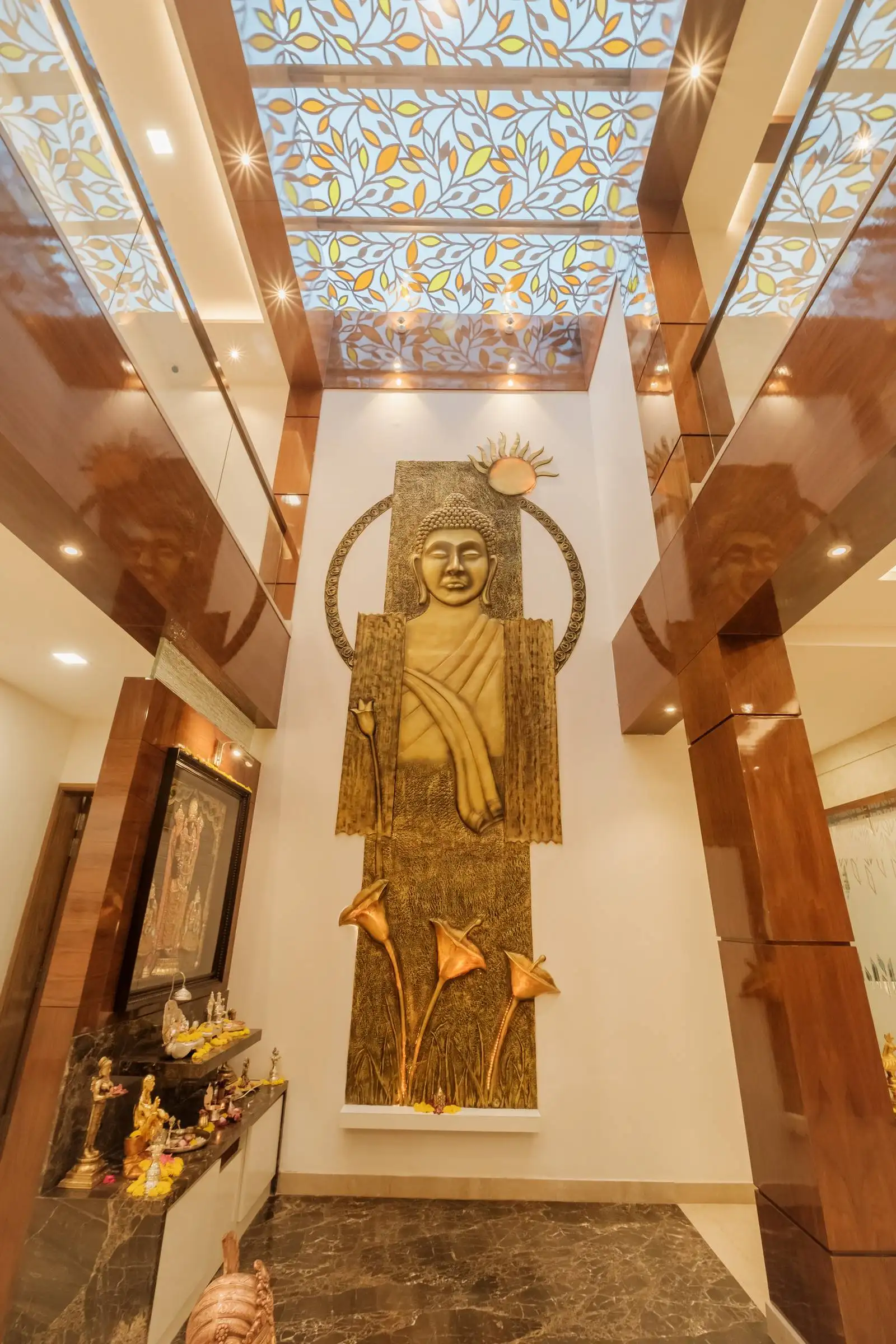 Double-height pooja space framed by glossy wooden columns and glass railings, creating a serene atmosphere with vertical volume and modern elegance.