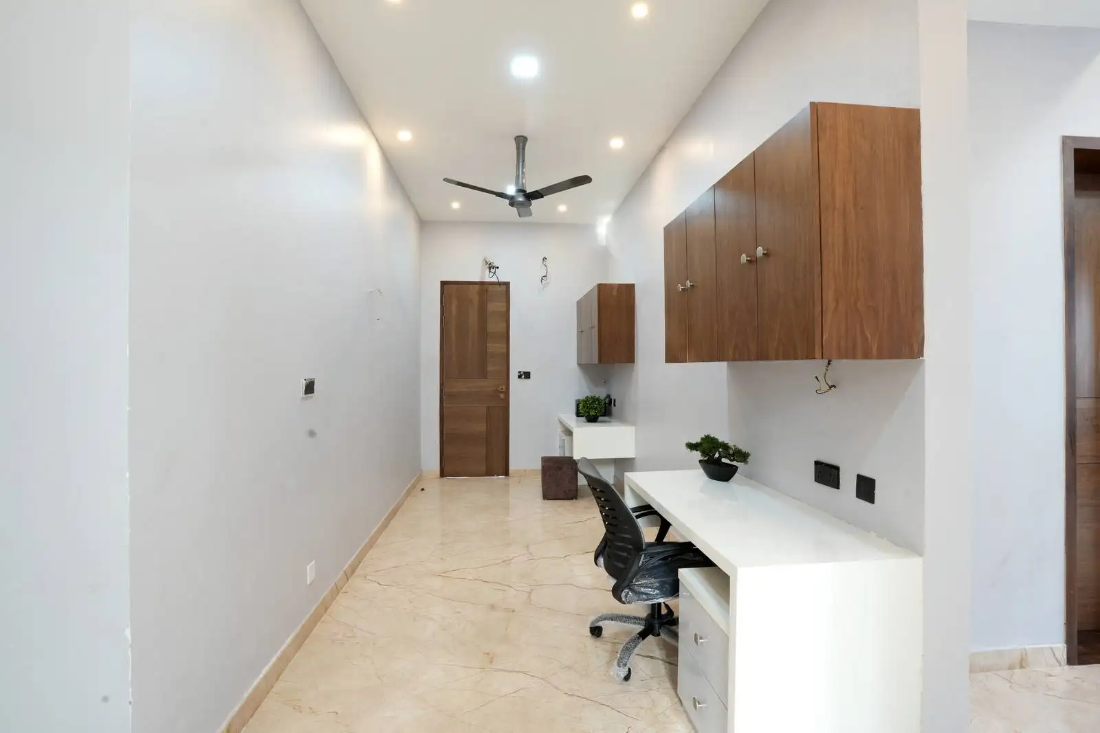 First-floor corridor-style office featuring built-in white workstations that optimize spatial efficiency and support a streamlined, functional workspace layout.