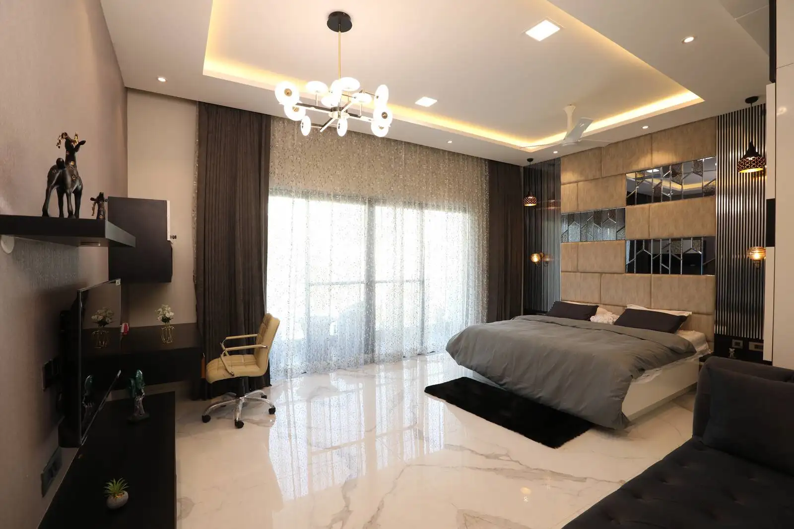 Luxurious bedroom with white marble flooring, reflective accents, heavy drapes, ceiling fan, and ample storage for comfort and functionality.
