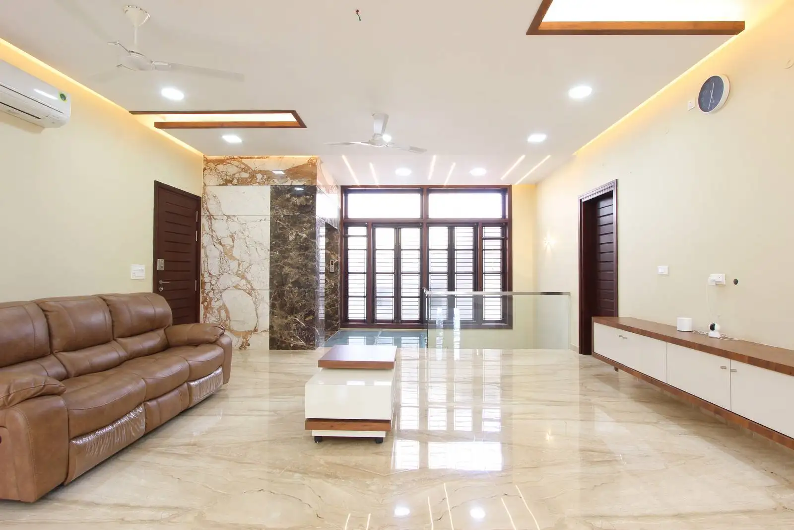 An open, marble-clad family lounge with an integrated lift, large window wall, and airy layout designed for relaxed gatherings and strong indoor-outdoor connection.
