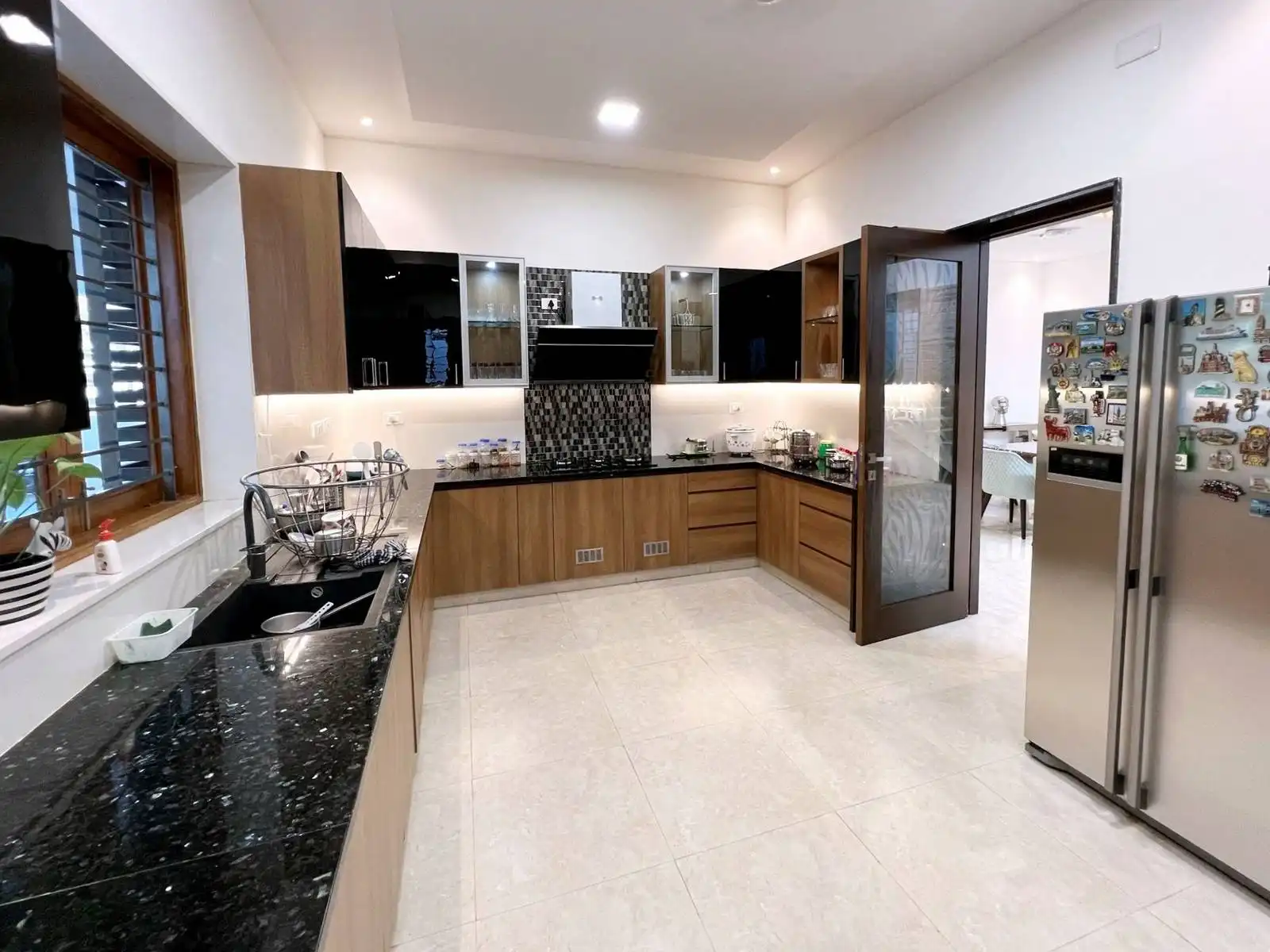 The countertops are finished in black granite, providing a durable, easy-to-clean, and visually striking work surface. The long counter under the window is ideal for food prep and dish drying.