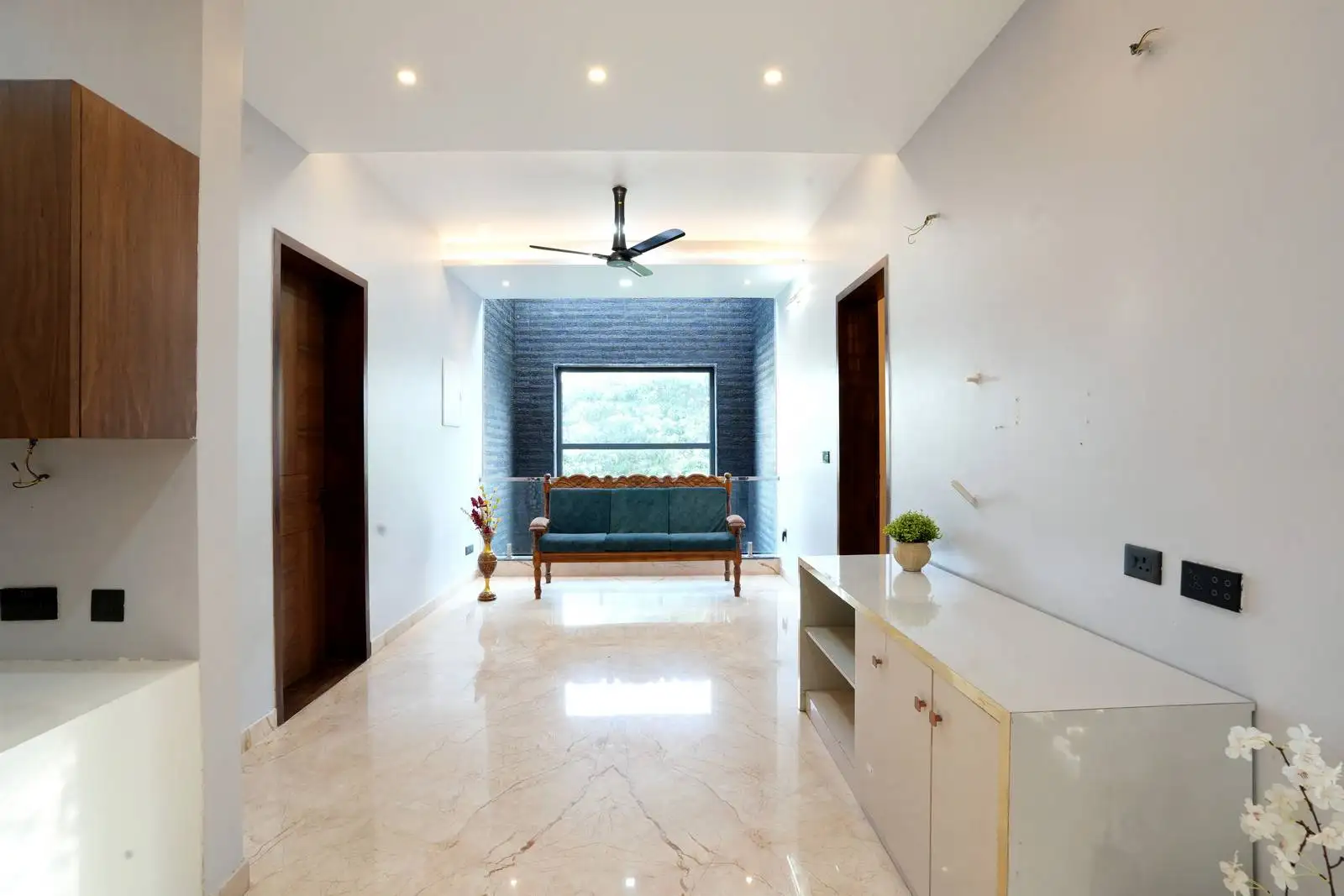 Family area featuring a traditional wooden settee positioned by a large window, designed to create a warm, inviting space for relaxation and gatherings.