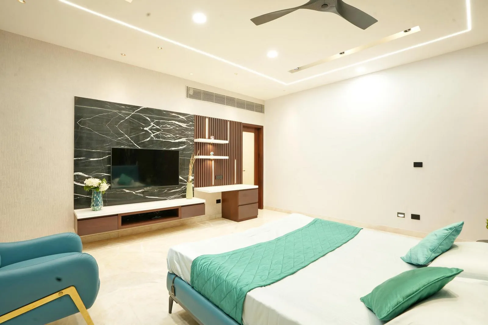 The false ceiling features recessed linear and cove lighting, casting a soft, ambient glow that highlights the room’s geometry. This subtle illumination enhances spatial depth and adds a modern, elegant touch to the interior.