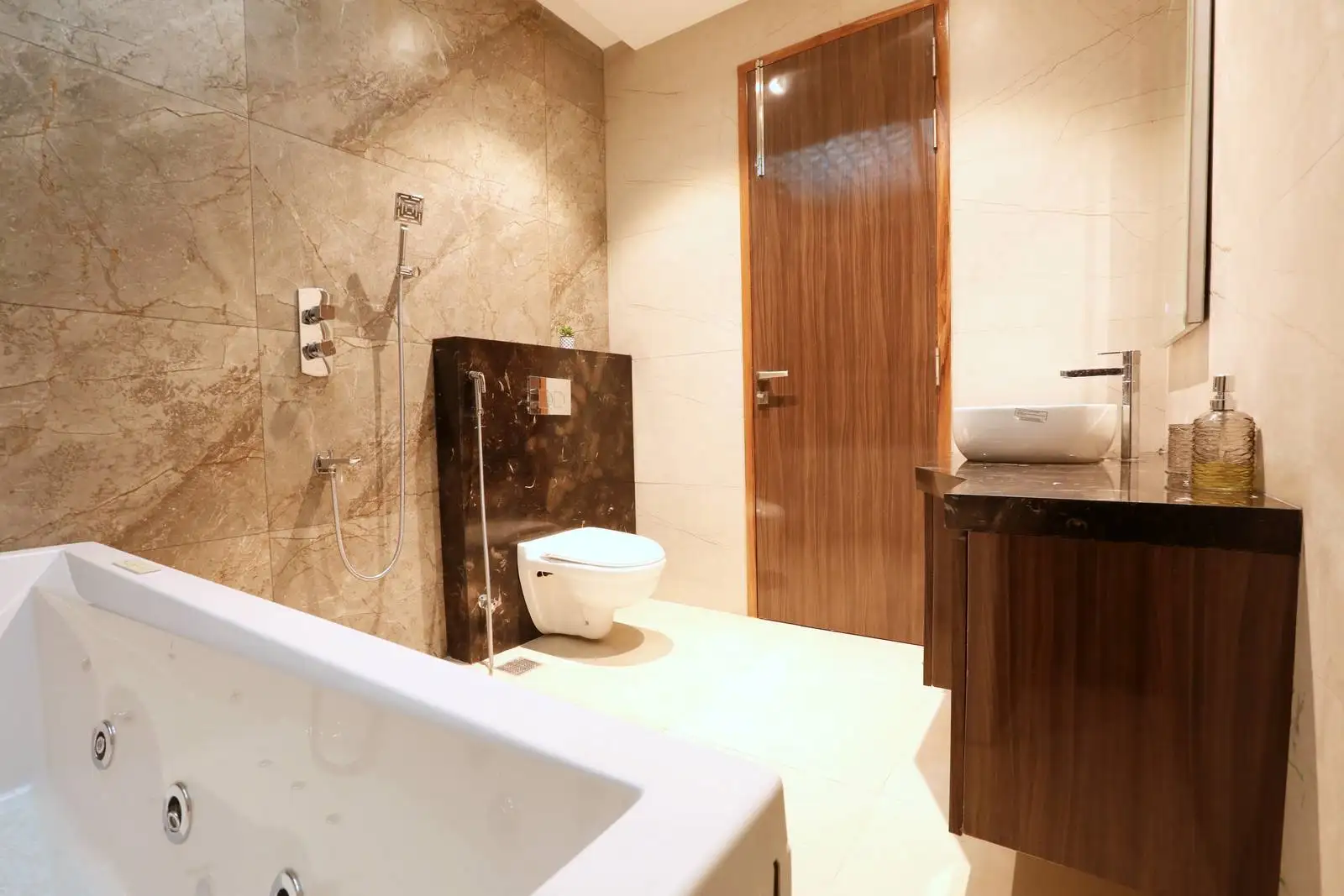Stylish bathroom showcasing a white bathtub, dark marble accent wall with wall-mounted toilet, and a warm wooden vanity for a balanced, contemporary design.