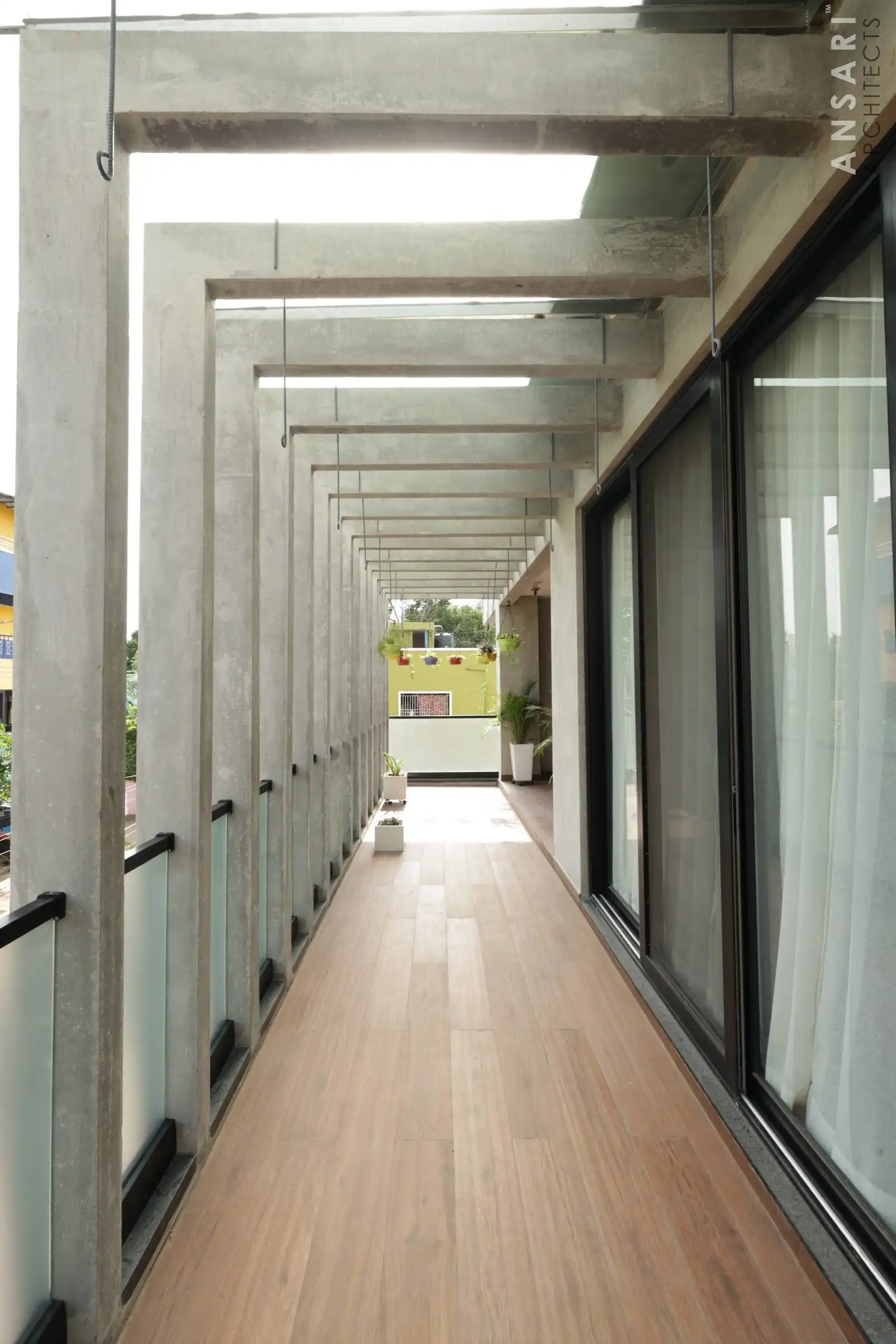 Exposed concrete beams and columns create a rhythmic framework along the balcony, adding depth and a bold architectural statement.