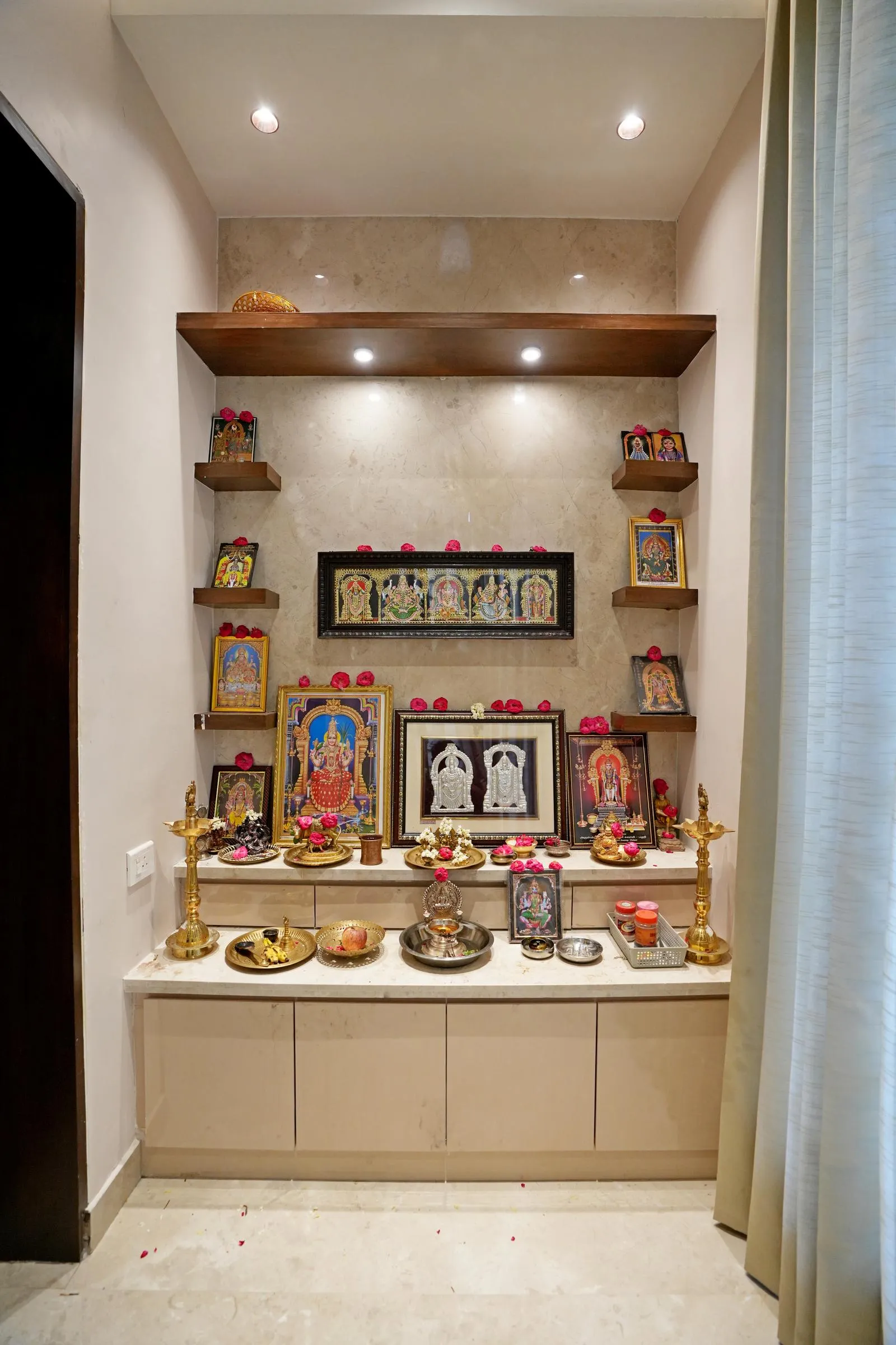 Pooja Room ( 8'0" x 5'0" sq.ft ) is a compact, serene niche designed for spiritual practice, featuring polished beige marble, natural wood shelves, and matte cream cabinetry. Recessed lighting, floating shelves, and brass accents create a calm, organized, and sacred atmosphere while maximizing functionality and visual harmony.