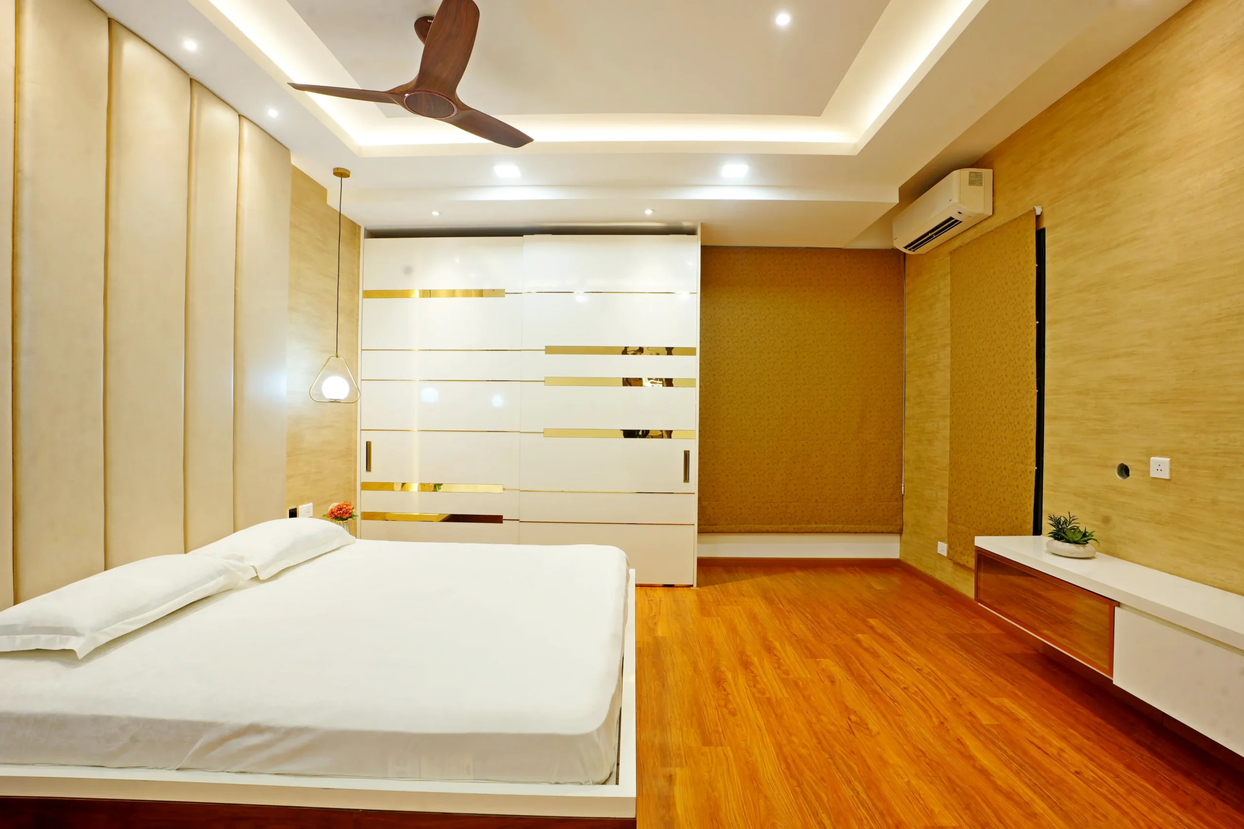 The bedroom features a symmetrical layout with a central bed and sliding wardrobe opposite, ensuring balance and efficient storage. The design creates a bright, airy, and functional space.