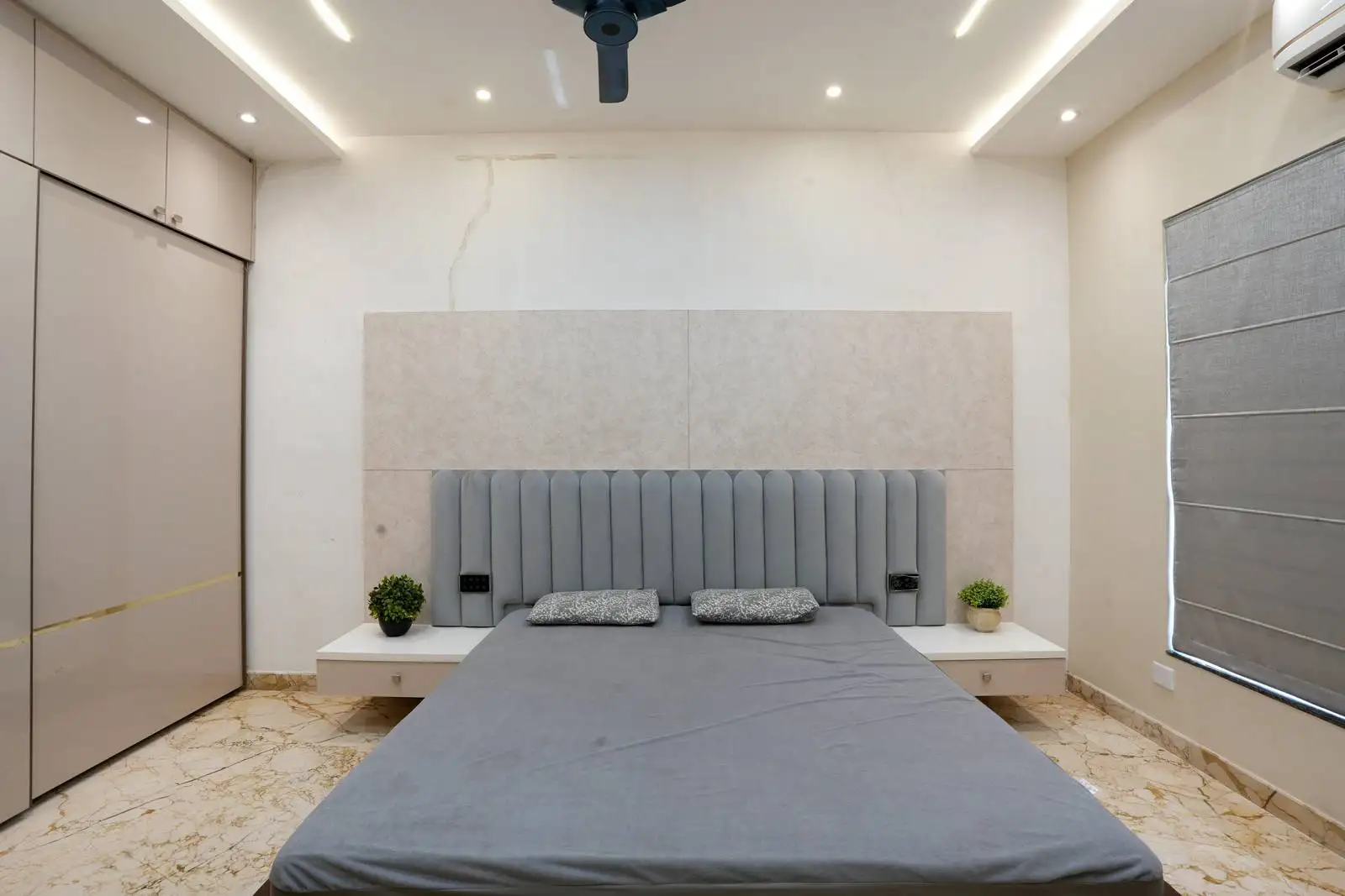The room features a soft neutral palette of grey, beige, and white for a calming, contemporary feel, complemented by grey blinds for privacy and light control.