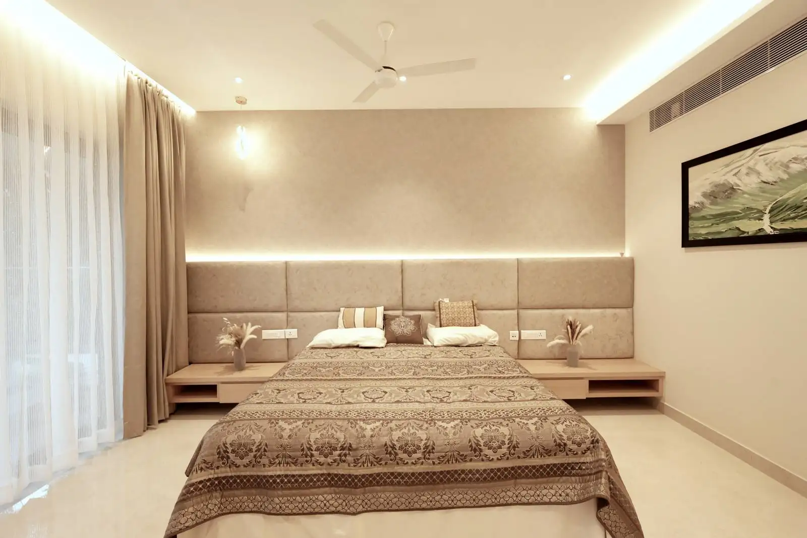 The headboard wall features upholstered panels in a neutral tone, adding texture and a soft, cozy feel.