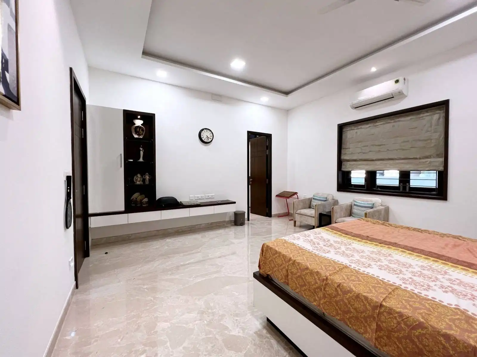 A spacious, minimalist bedroom with polished marble floors, window-side seating, and abundant natural light for a serene retreat.