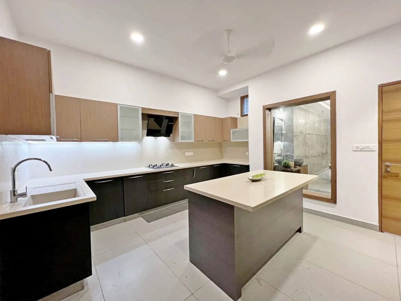 The kitchen combines U-shaped workflow, matte black and oak cabinetry, and quartz surfaces for a sleek, functional, and minimalist design. Natural light, frosted glass panels, and integrated LED lighting enhance openness, efficiency, and visual harmony.