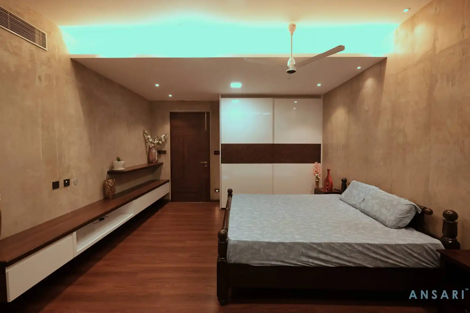 Polished wooden flooring adds warmth and continuity, while a seamlessly integrated door enhances the bedroom cohesive design.