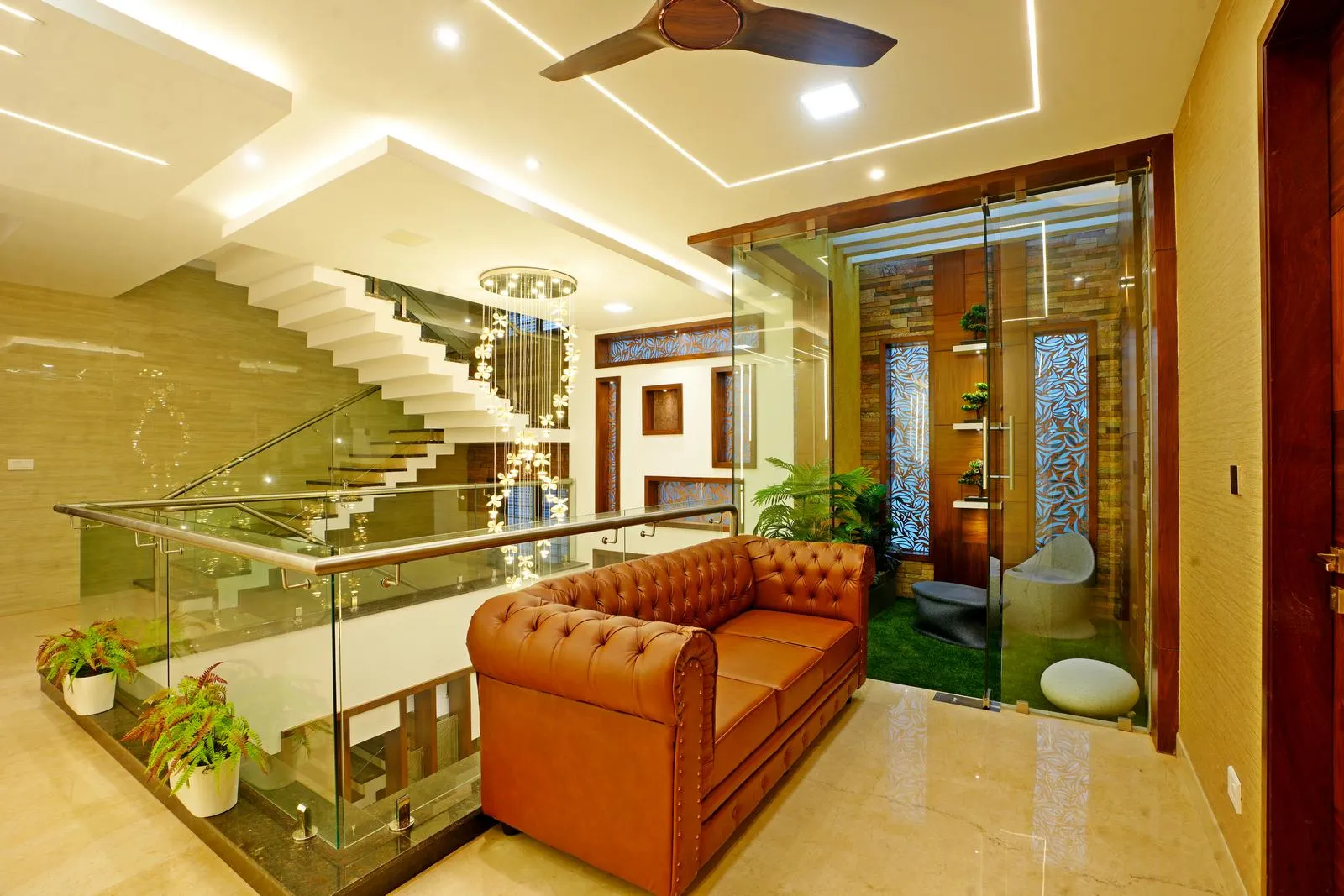 The family area near the staircase and courtyard acts as a fluid transitional space. Neutral marble finishes, warm wood accents, and layered lighting create a bright, open, and well-connected space.
