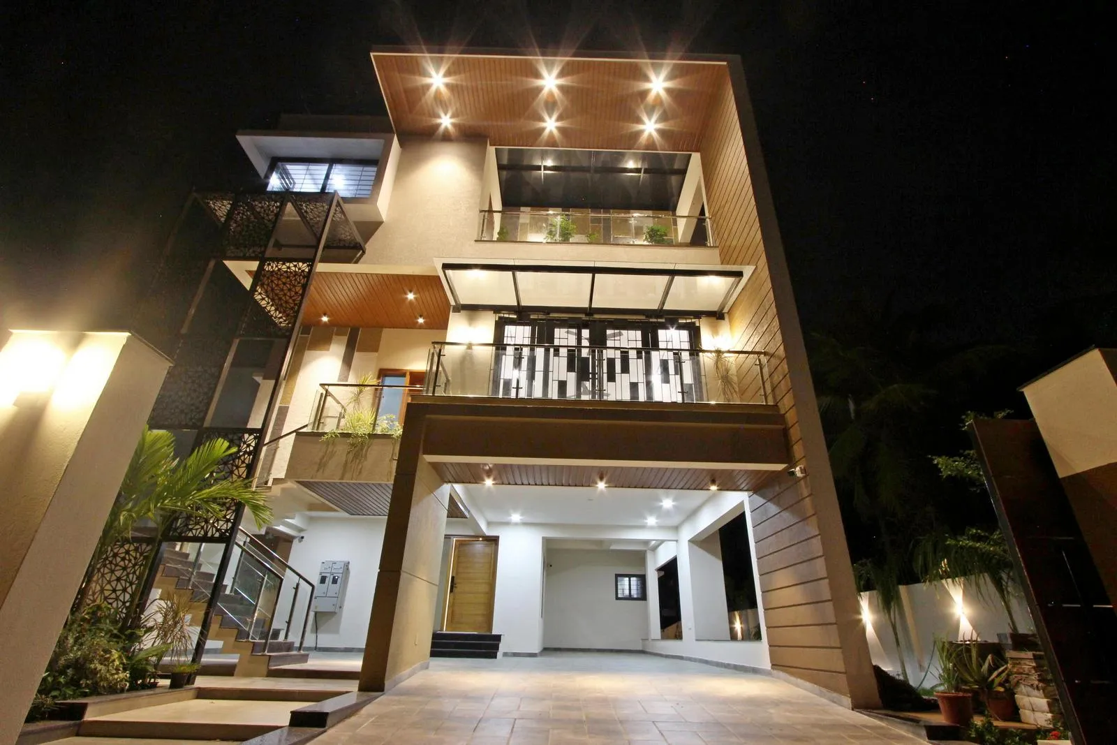 Lighting accentuates the cantilevered roof, vertical planes, and wood textures, adding depth and warmth. 