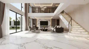 Modern living room with large marble tiled floor, floor-to-ceiling windows with curtains, a seating area with gray armchairs and a sofa, a wall-mounted TV on a marble accent wall, and a marble staircase with illuminated steps leading to an upper floor balcony.
